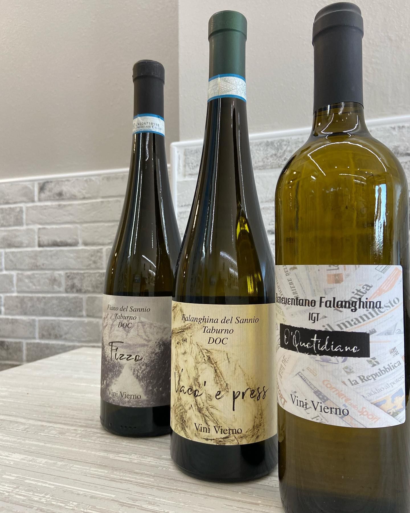 Tre bottiglie di vino con etichette colorate su un bancone.