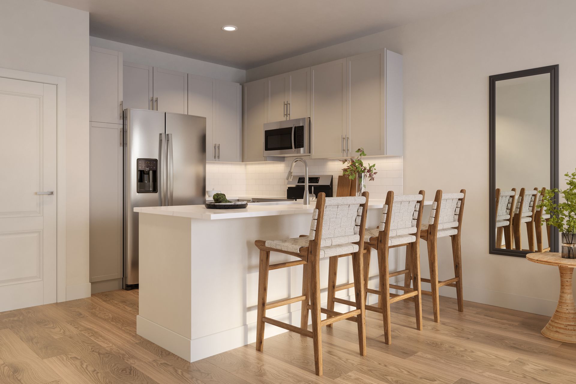 Modern kitchen featuring a white island with three stools, stainless steel appliances, and a wall mirror.