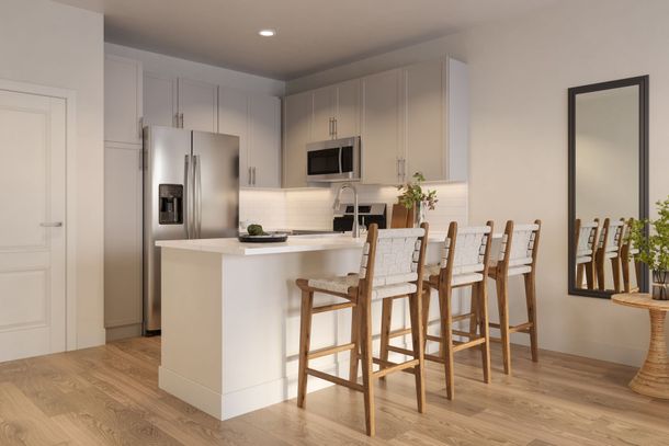 Modern kitchen featuring a white island with three stools, stainless steel appliances, and a wall mirror.