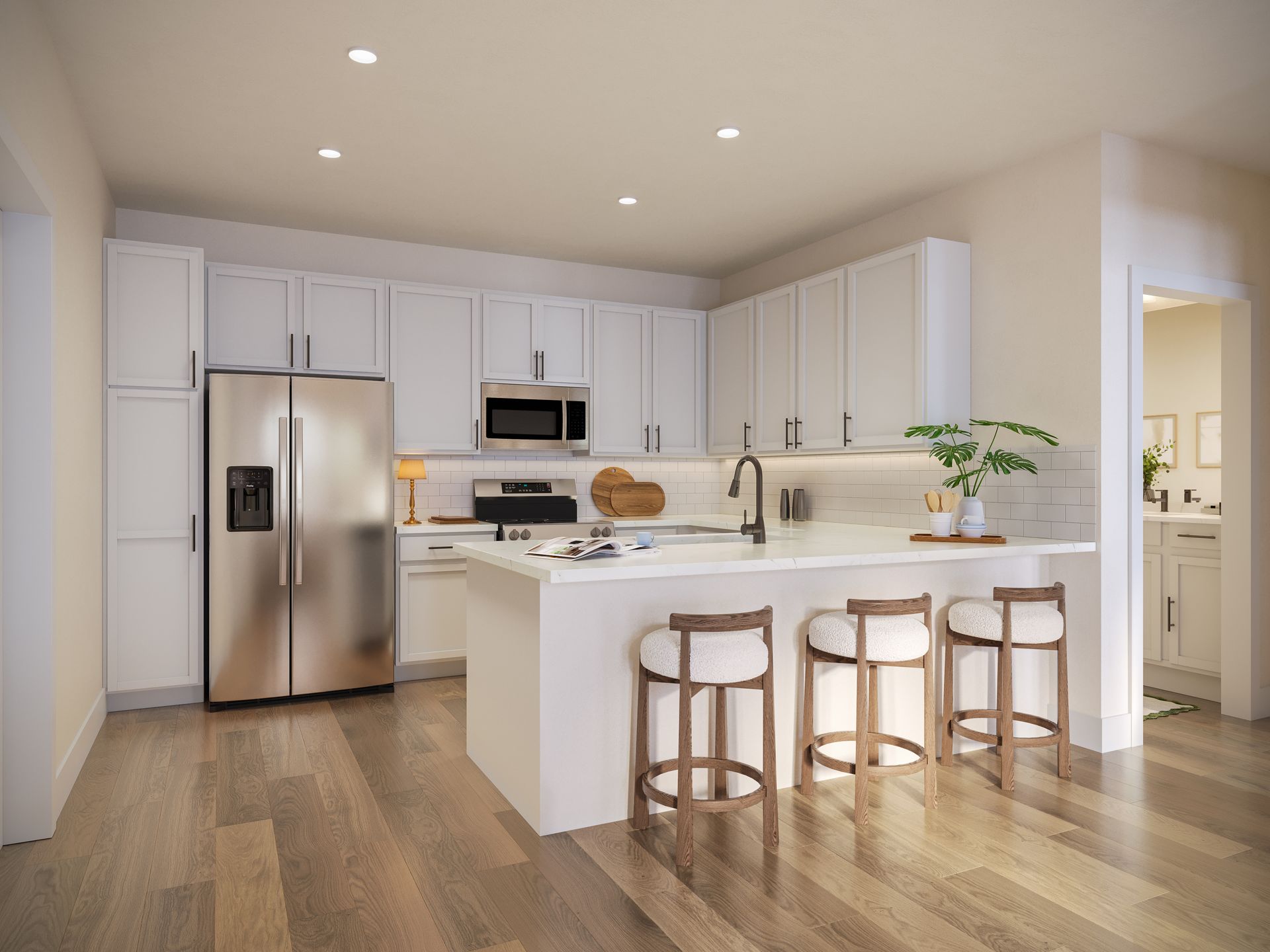 A modern kitchen featuring white cabinets, stainless steel appliances, a center island with three stools, and wood floors.
