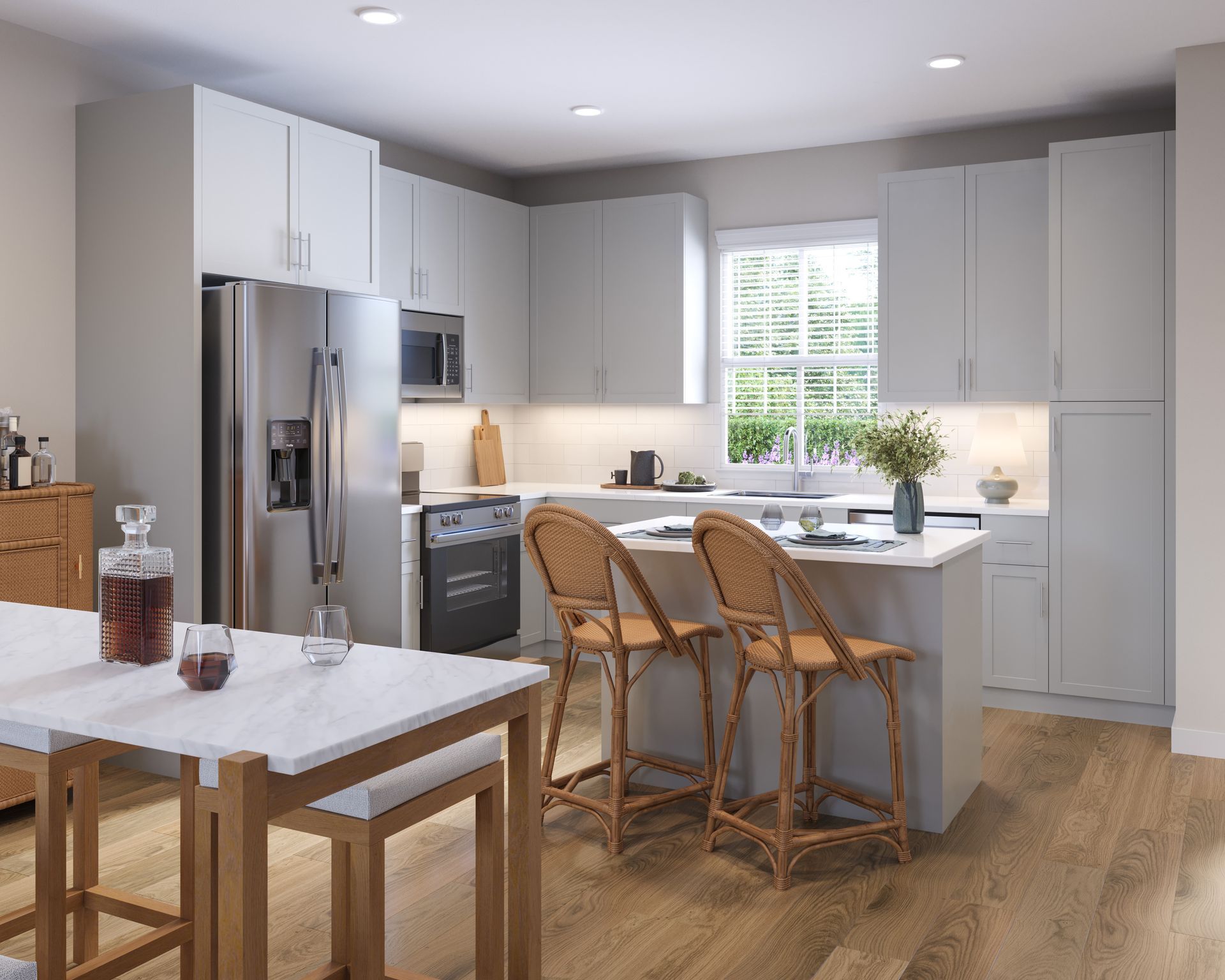 Modern kitchen with light gray cabinets, stainless steel appliances, a white island with wicker stools, and wood flooring.