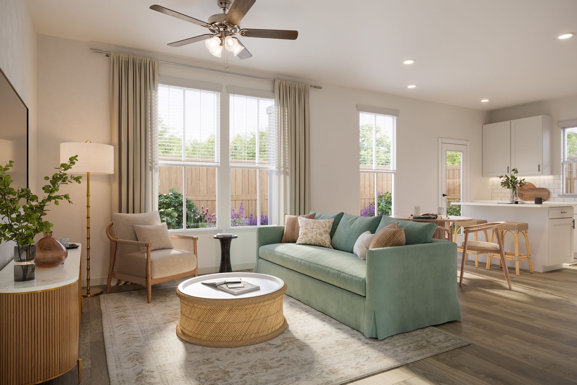 Bright open-concept living room with a sage green sofa, a round woven coffee table, and an adjacent modern kitchen area.