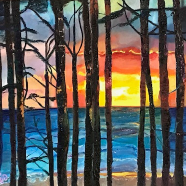 Vibrant sunset over a blue sea viewed through a silhouette of tall pine trees on a sandy beach.