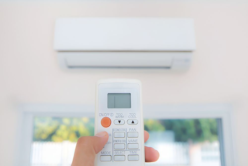 A Person Is Holding A Remote Control — BT Airconditioning In Smithfield, QLD