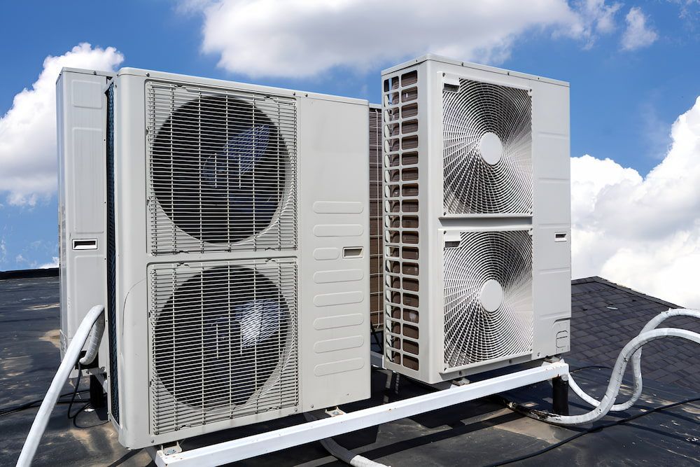 Two Air Conditioners Are Sitting On Top Of A Roof — BT Airconditioning In Portsmith, QLD