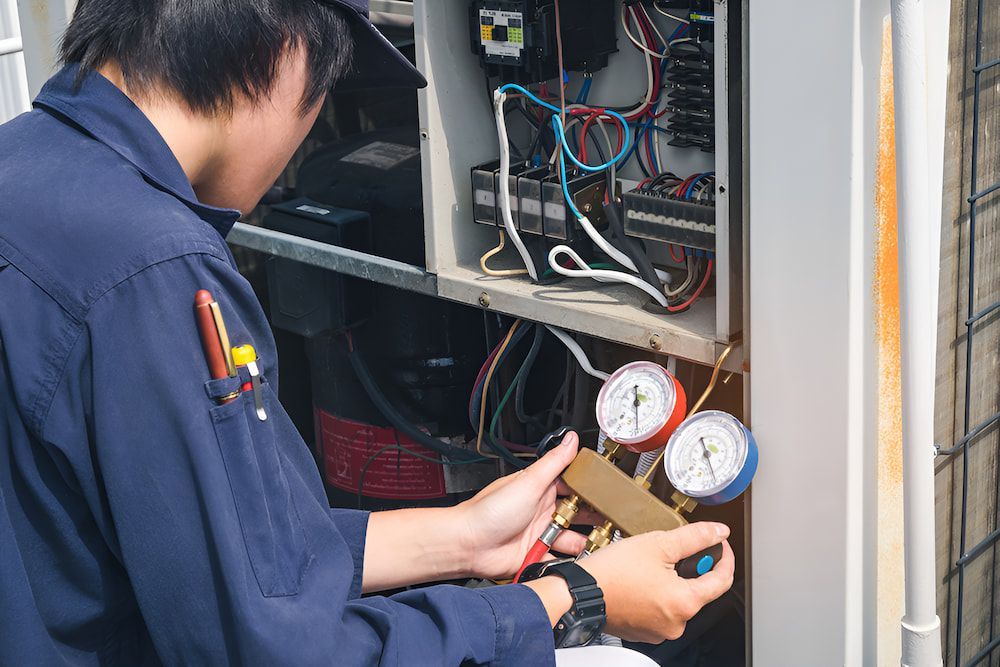 A Man Is Working On A Airconditioner — BT Airconditioning In Portsmith, QLD