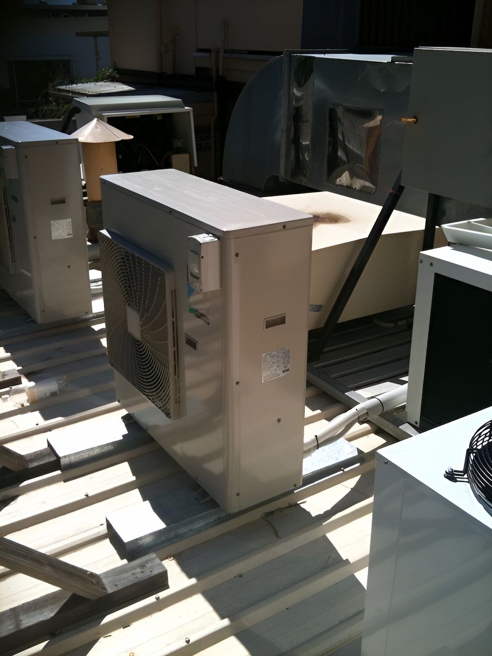 A Row Of Air Conditioners Are Sitting On Top Of A Wooden Roof — BT Airconditioning In Portsmith, QLD