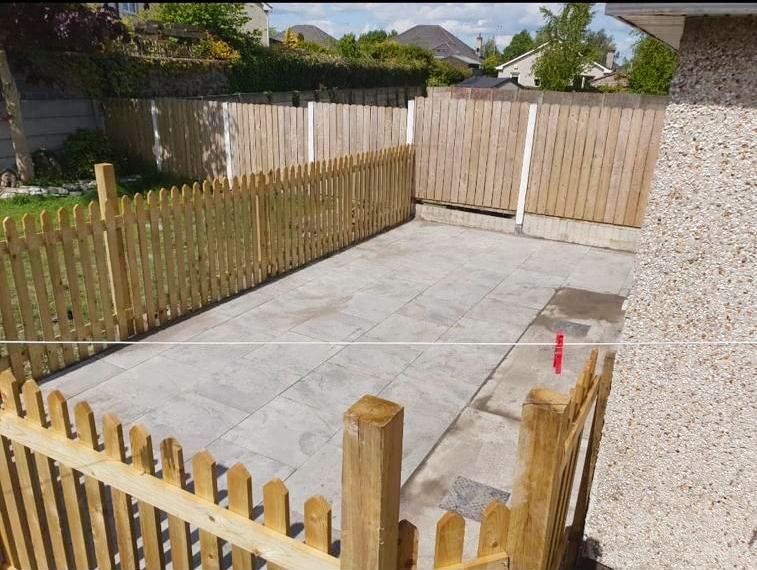 A wooden picket fence surrounds a concrete patio