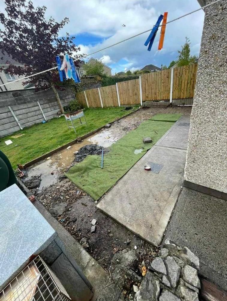 A dirty backyard with clothes hanging on a clothes line.