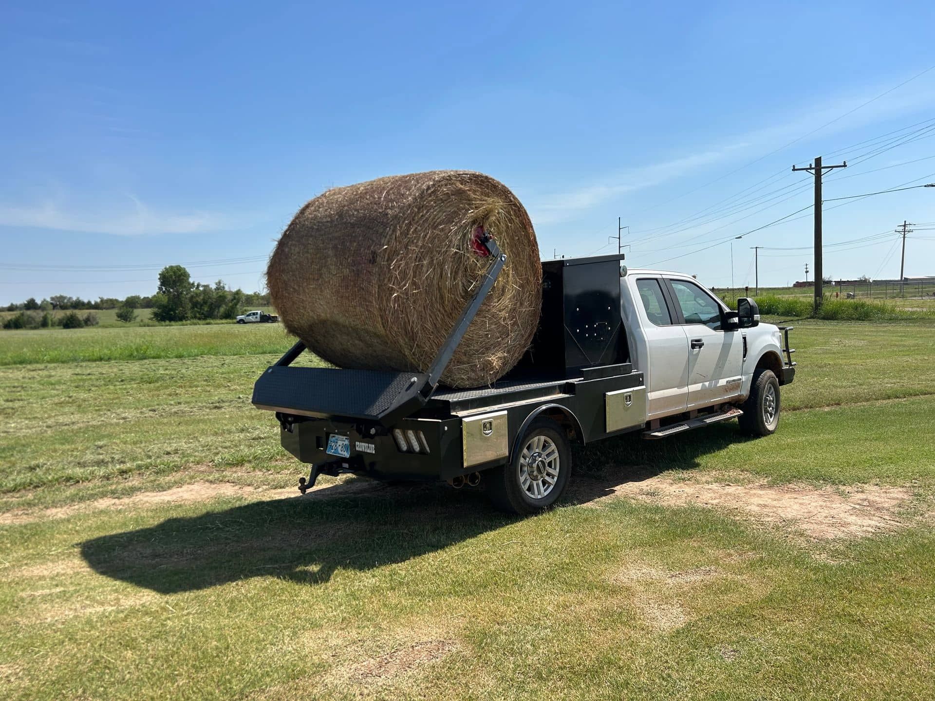 Crownline arm bed with round bale being loaded on flatbed