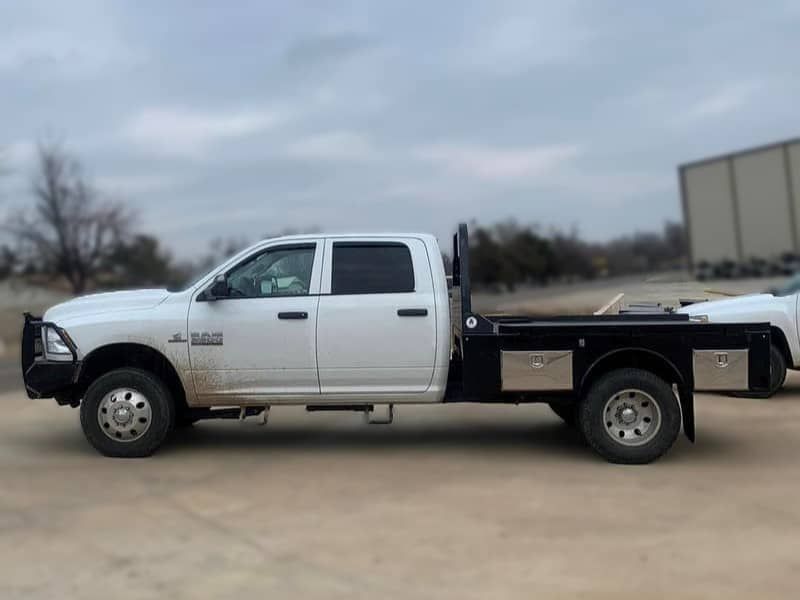 a white Ford truck with a flatbed is parked in a dirt field .