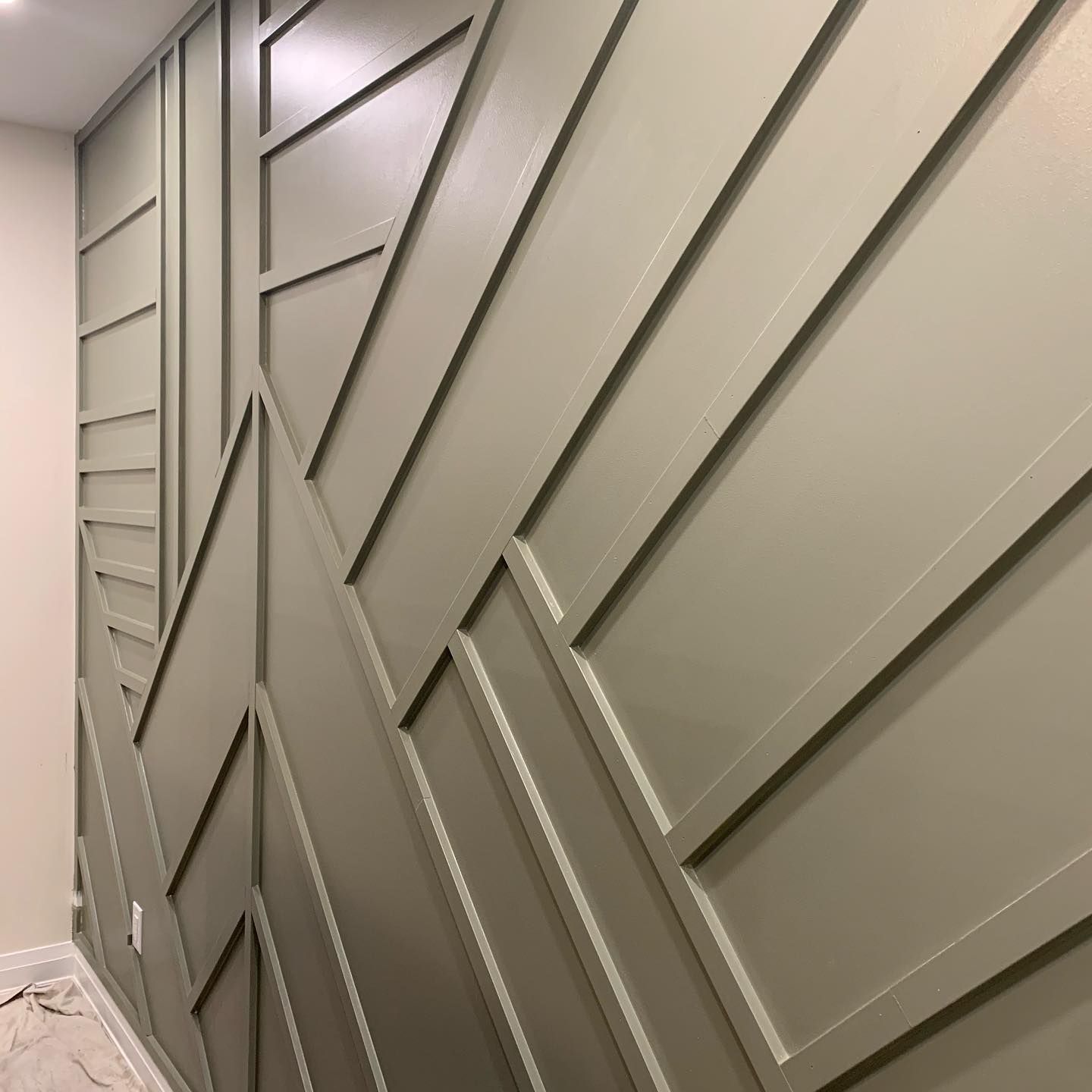 Modern gray paneled accent wall with geometric trim in a hallway or room corner