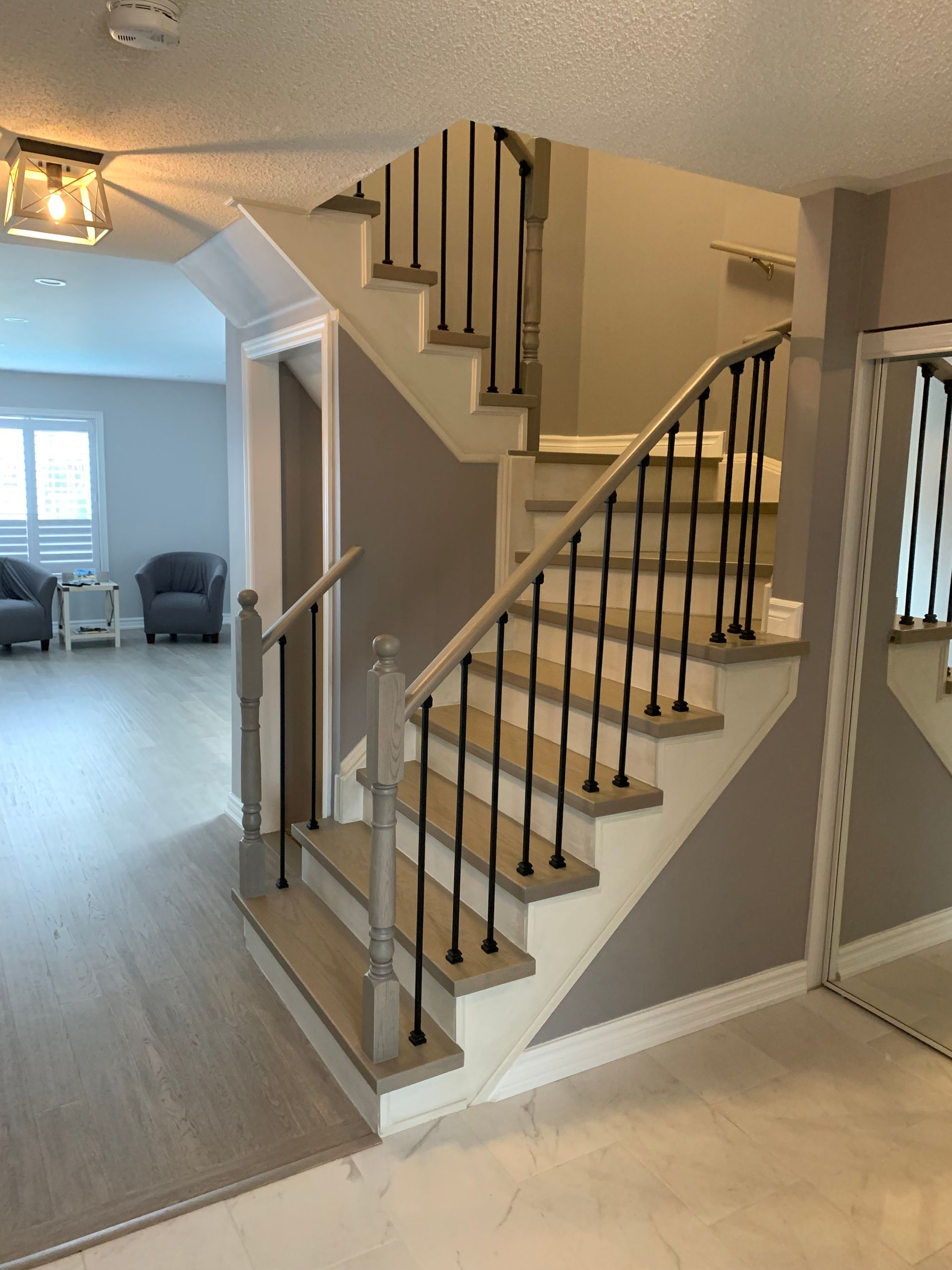 Indoor staircase with black railings and beige walls in a bright home entryway