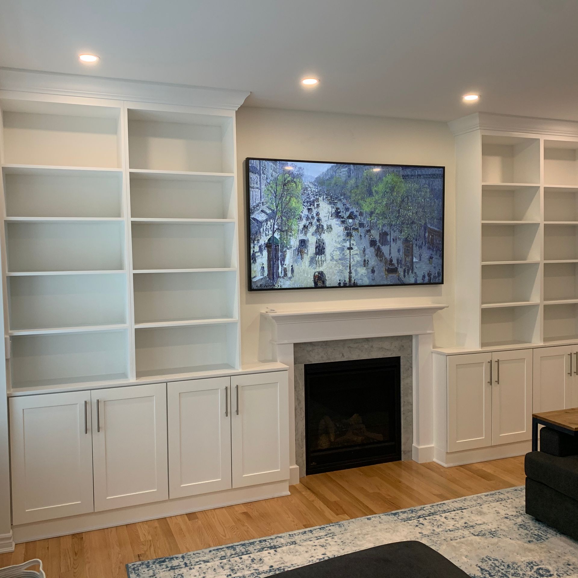 Modern living room wall with built-in white shelves, a fireplace, and a TV above it