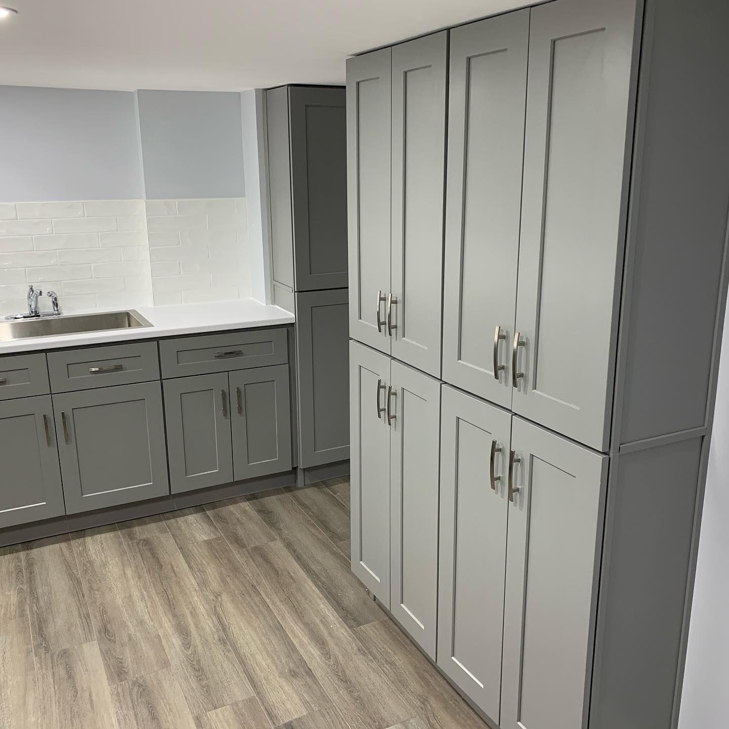 Modern kitchen with gray cabinets, white countertops, and wood-look flooring