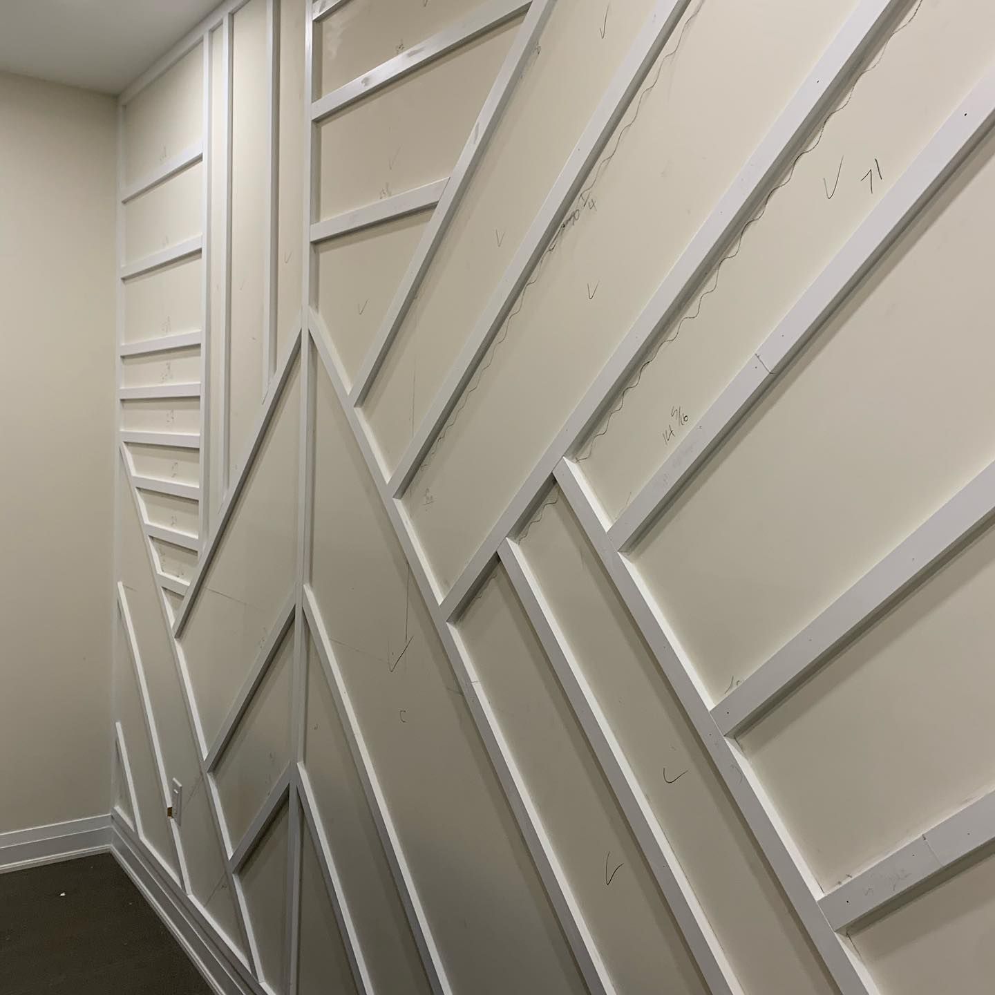 Beige hallway wall with geometric white trim panels and moldings.