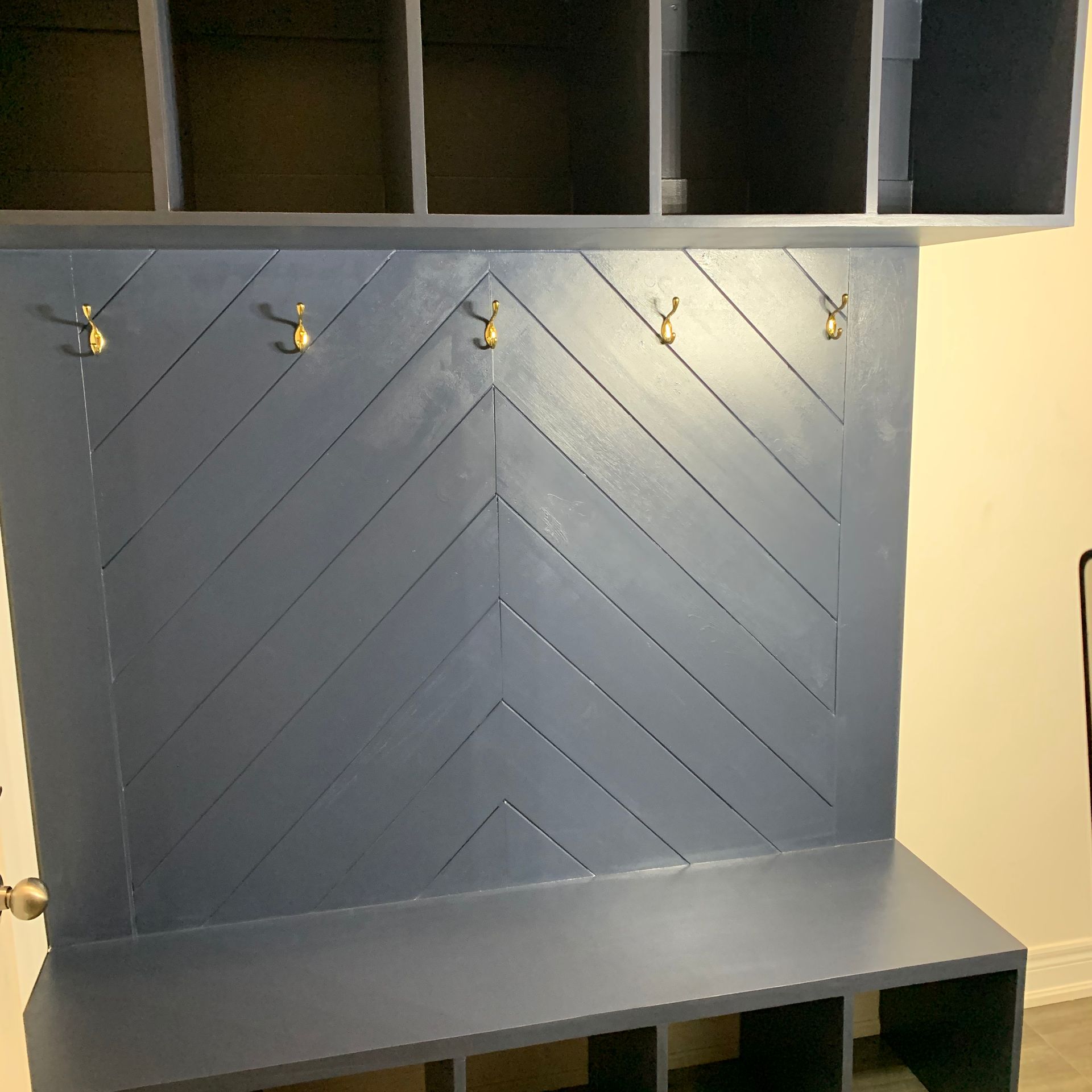 Blue built-in desk nook with chevron-patterned wall, cubby shelves, hooks, and a countertop
