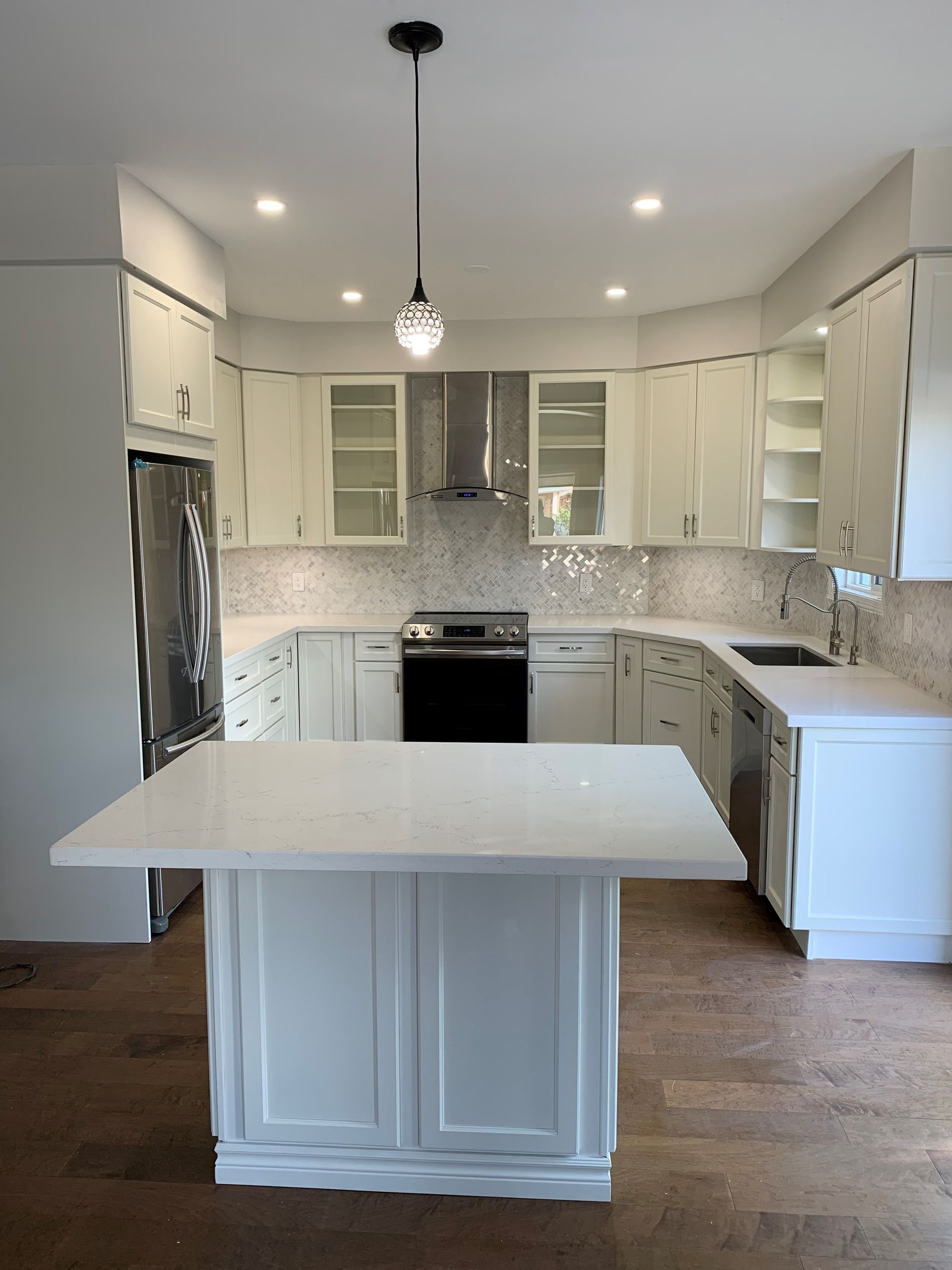 Bright white kitchen with island, stainless appliances, pendant light, and wood floors