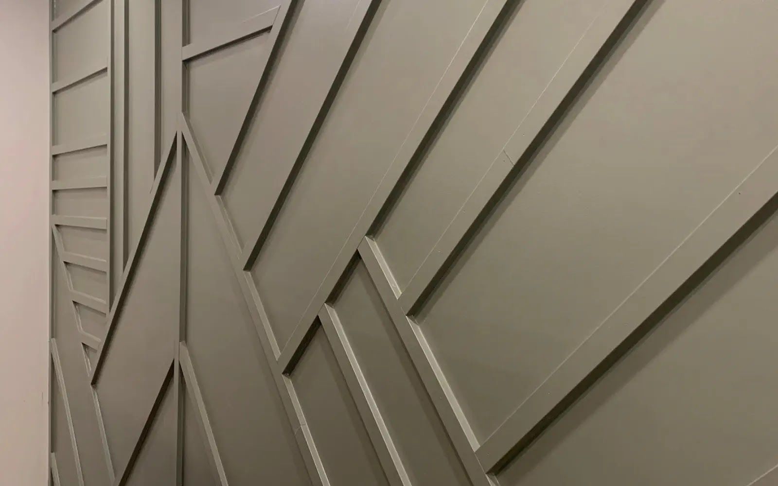 Gray geometric wall paneling with diagonal wood slats on an exterior building wall