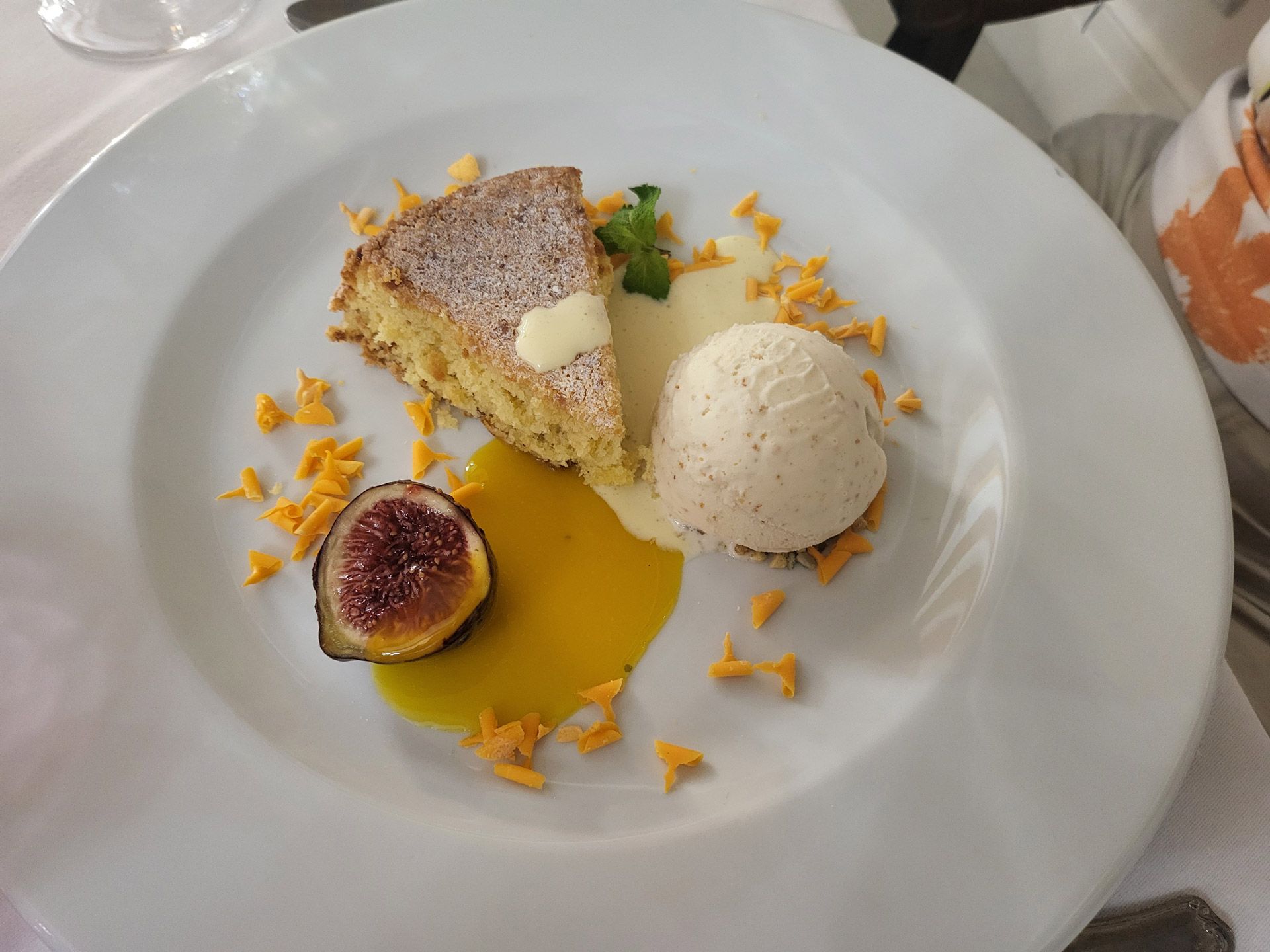 Restaurant table set with white tablecloth, food, wine glasses.
