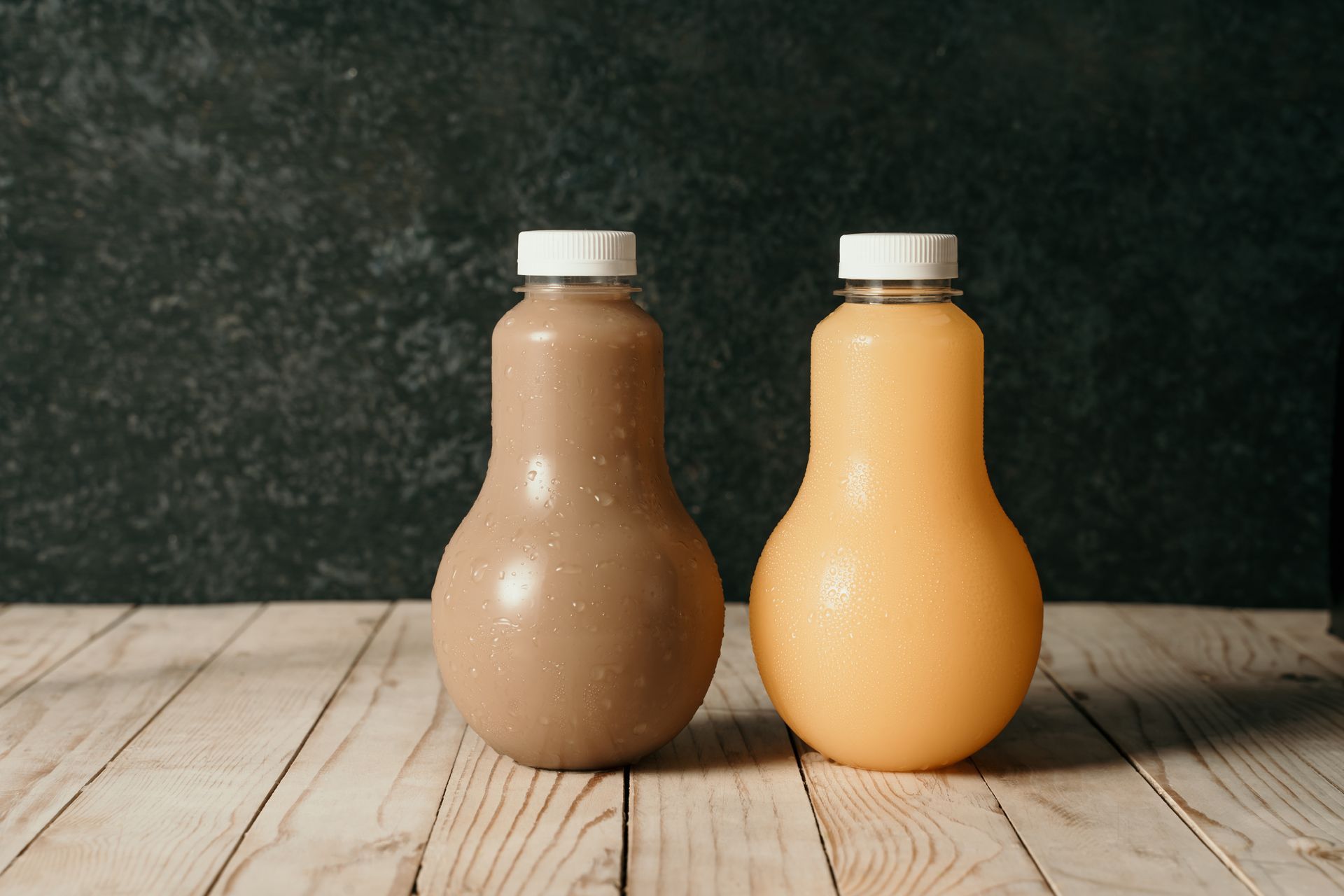 Two bottles of juice are sitting on a wooden table.