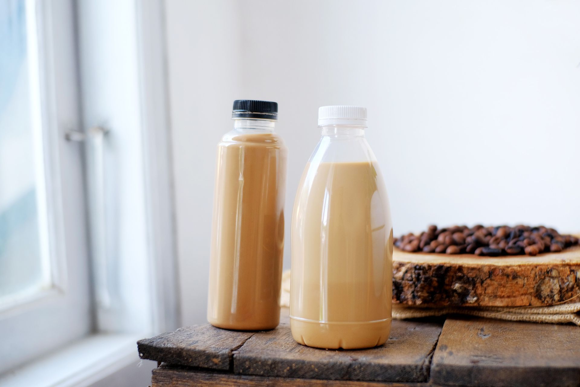 Two bottles of coffee are sitting on a wooden table.