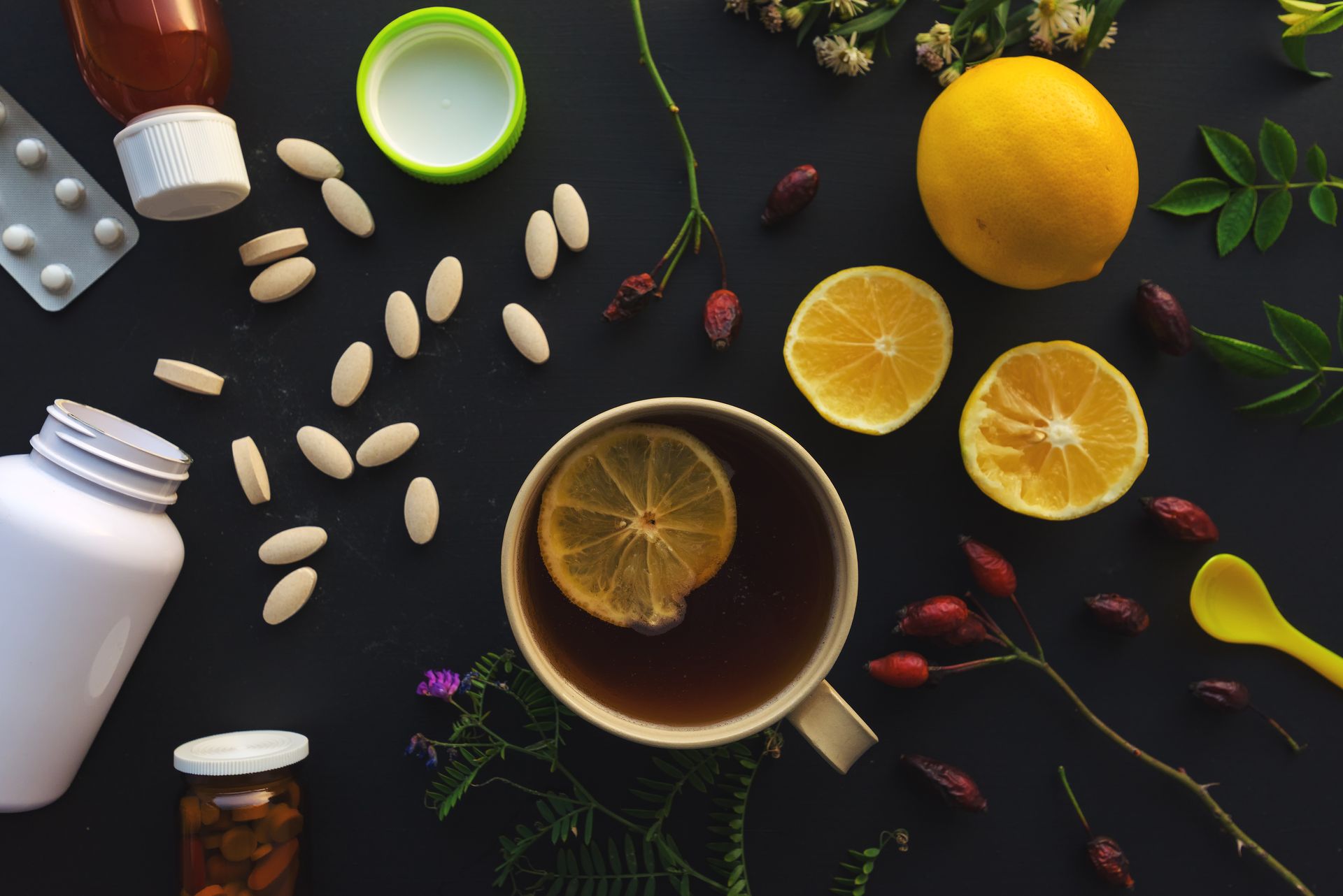 A cup of tea with lemon slices and pills on a table.