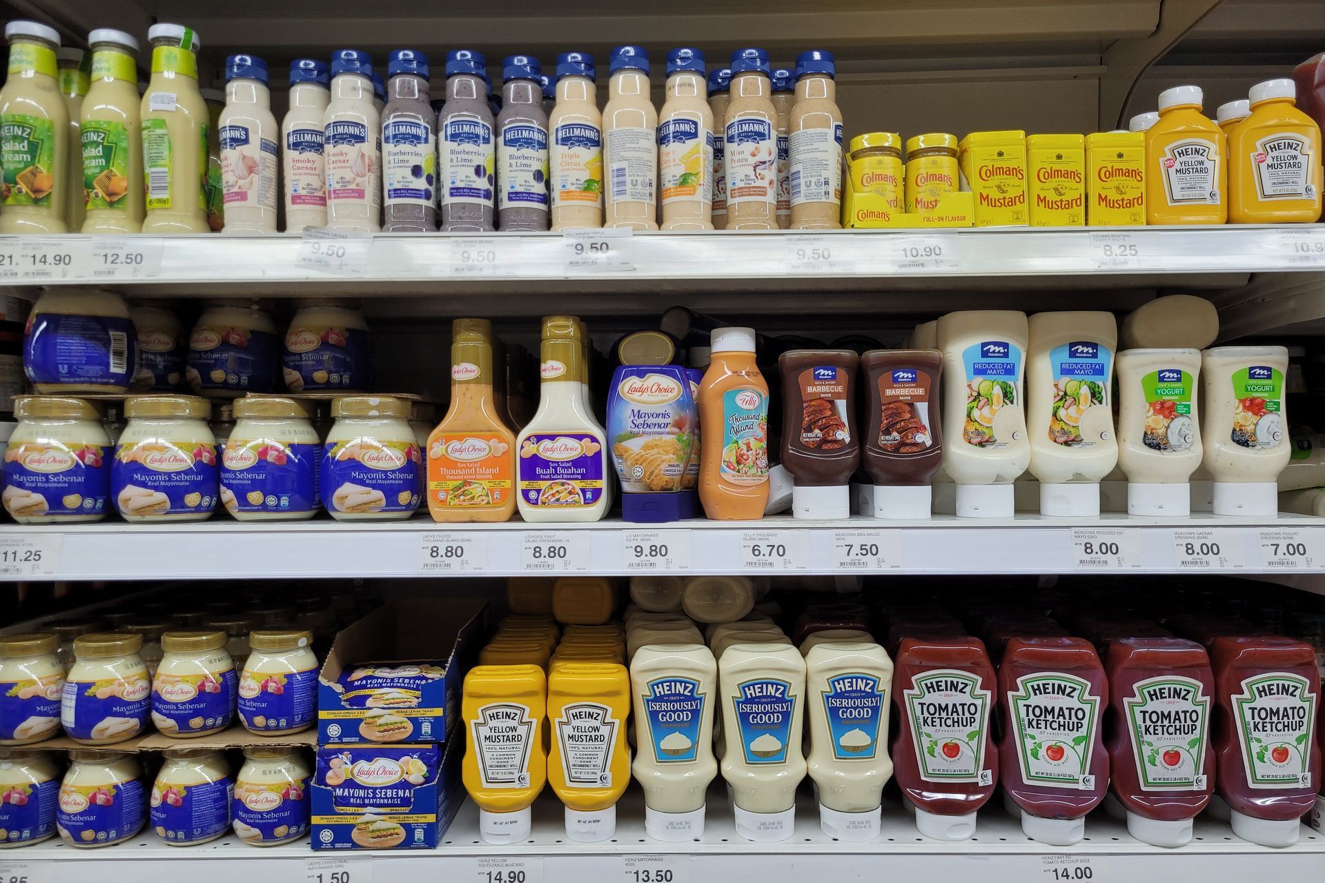 A grocery store shelf filled with condiments including ketchup and mayonnaise