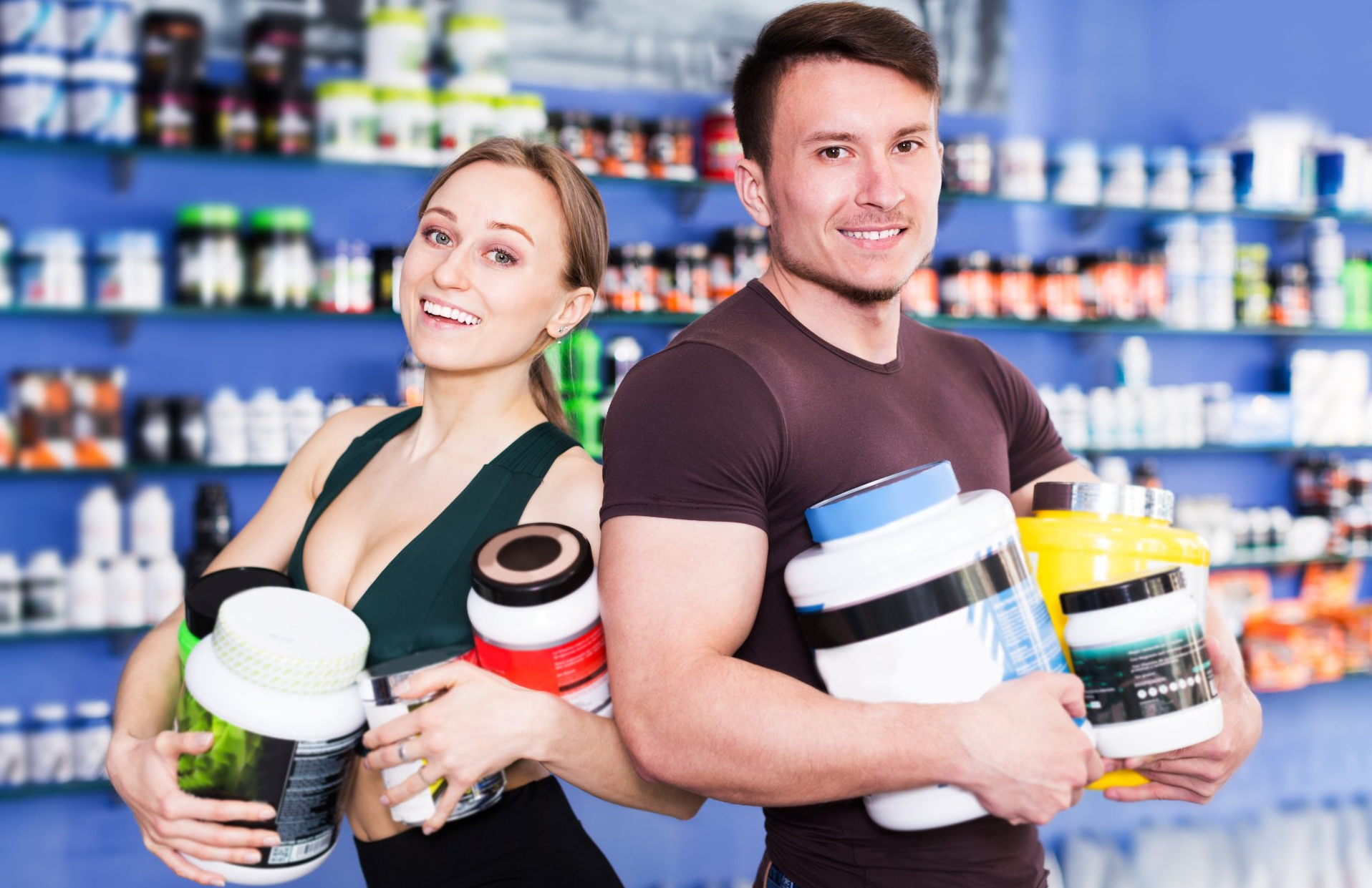 A man and a woman are holding protein powders in a store.