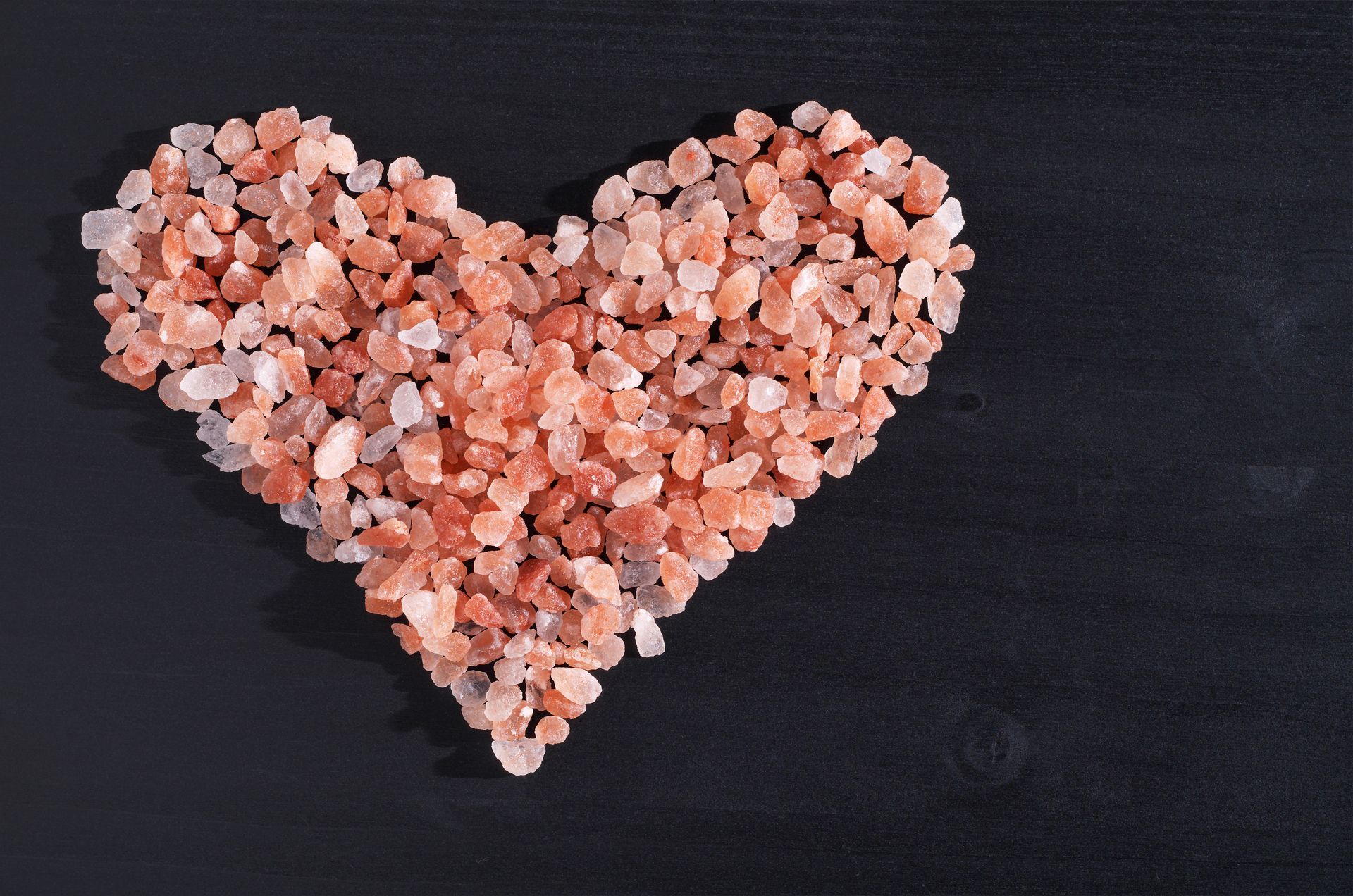 A heart made out of salt crystals on a black surface