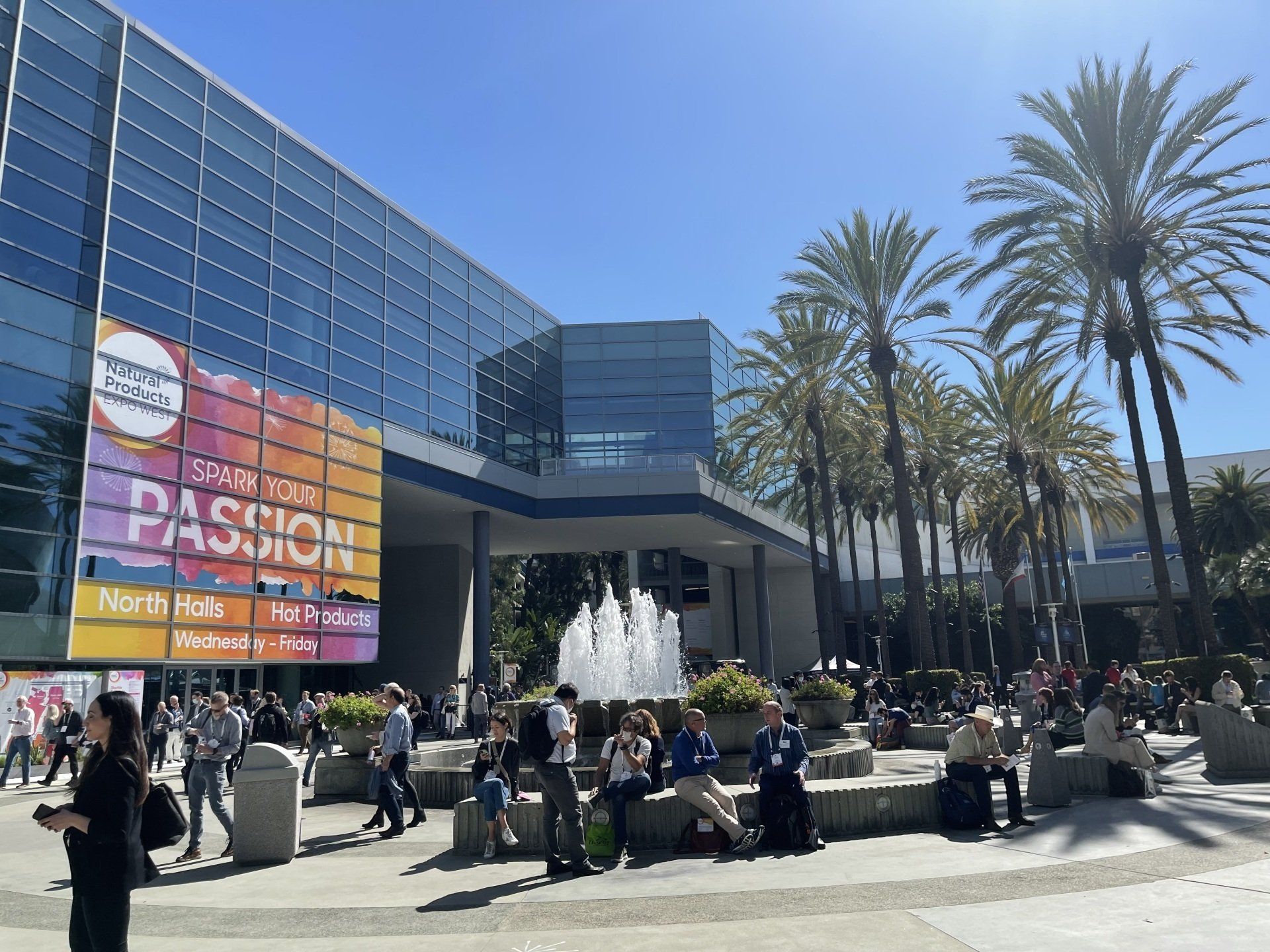 Image of people outside a building hosting Natural Products Expo West, with palm trees