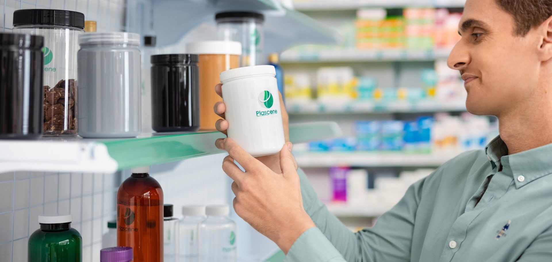 A man is holding a jar of pills in a pharmacy.