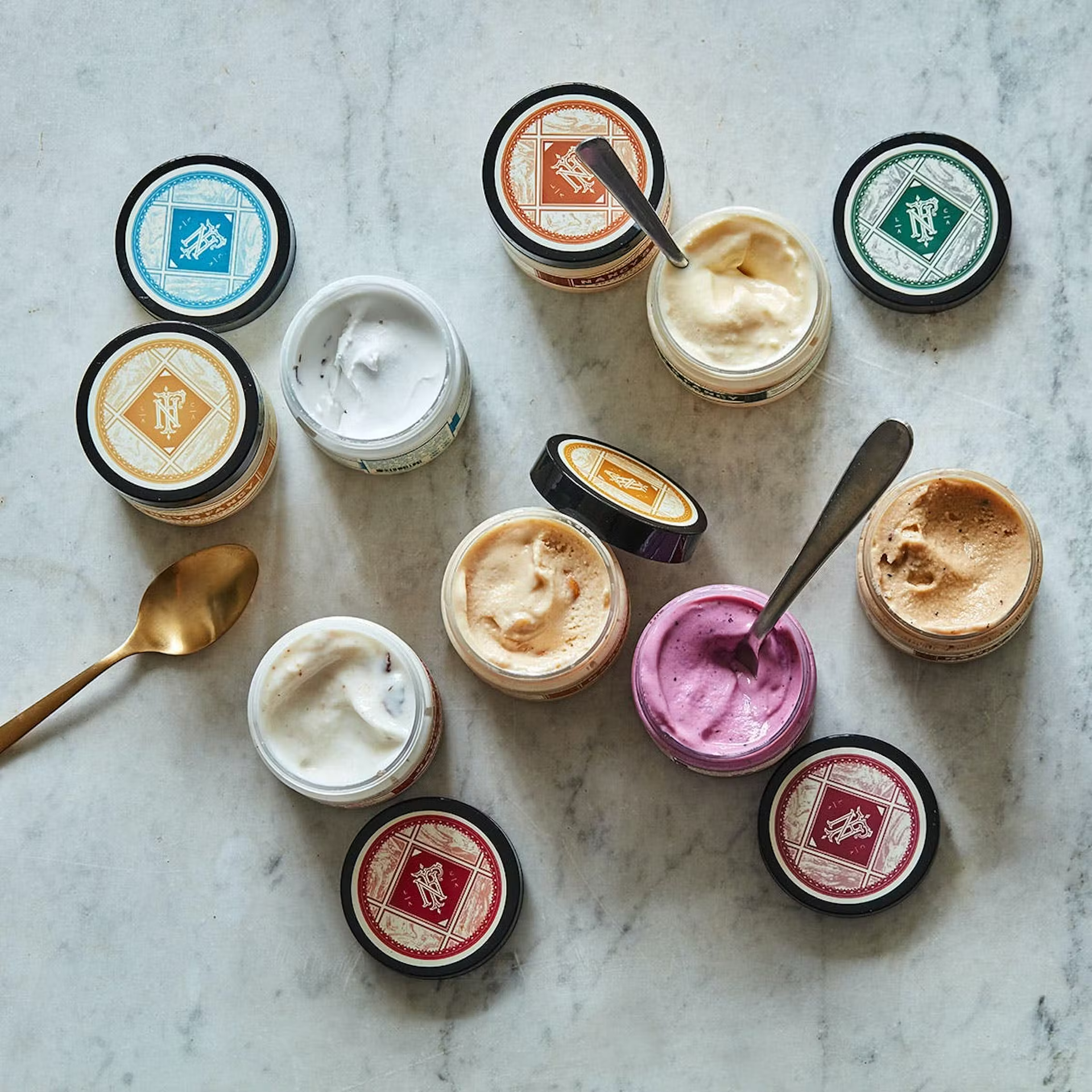 A spoon is sitting on a table surrounded by jars of ice cream