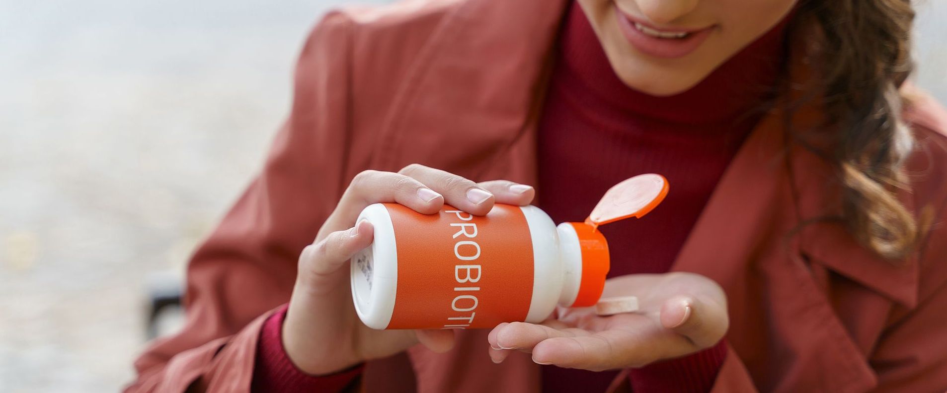 A woman is taking a pill from a bottle.