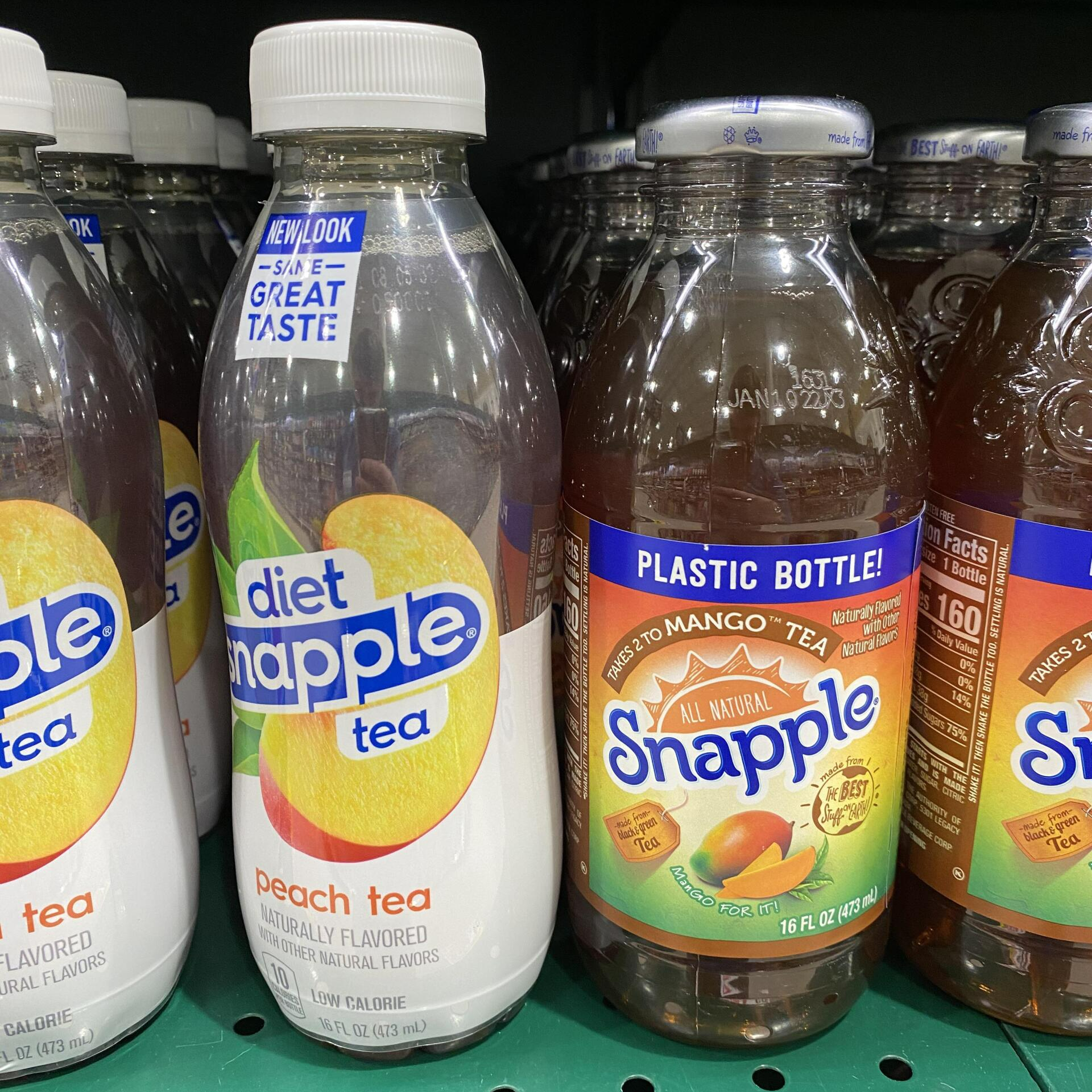 Snapple's 100% recyclable plastic bottle next to the old style Snapple bottle  with metal cap.