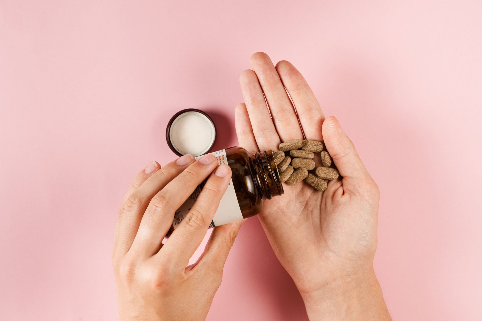 A woman is pouring pills from a bottle into her hand.