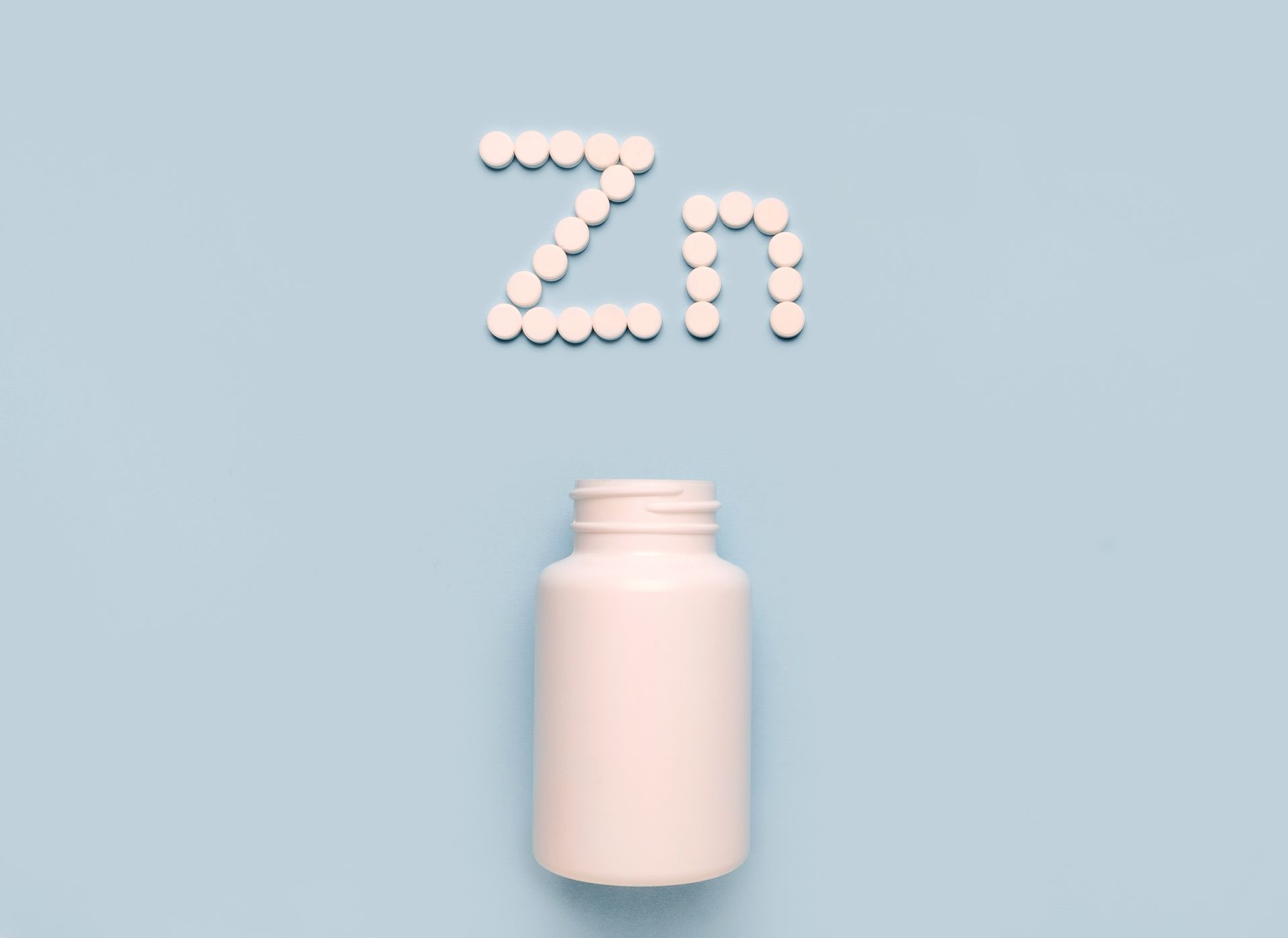 A bottle of pills and the word zn written in pills on a blue background.