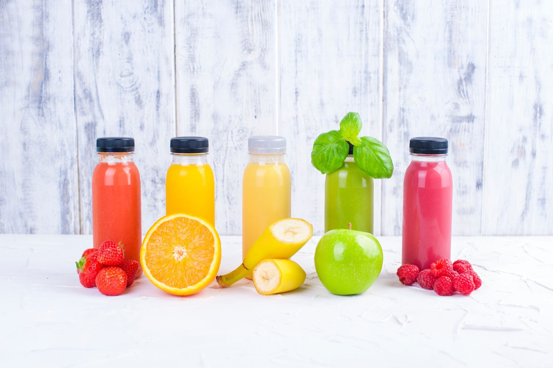 Variety of cold-pressed juice flavors--strawberry, orange, banana, apple, and raspberry--in PET plastic bottles.