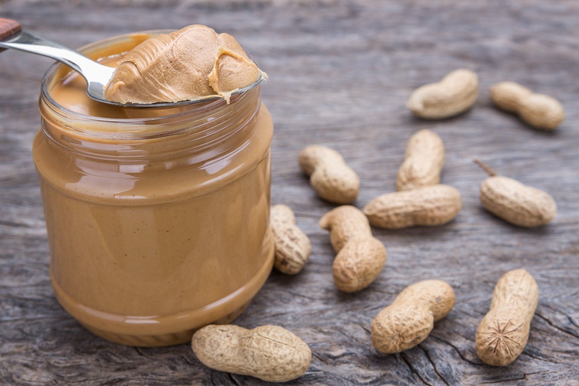 Spoon scooping peanut butter out of a jar.