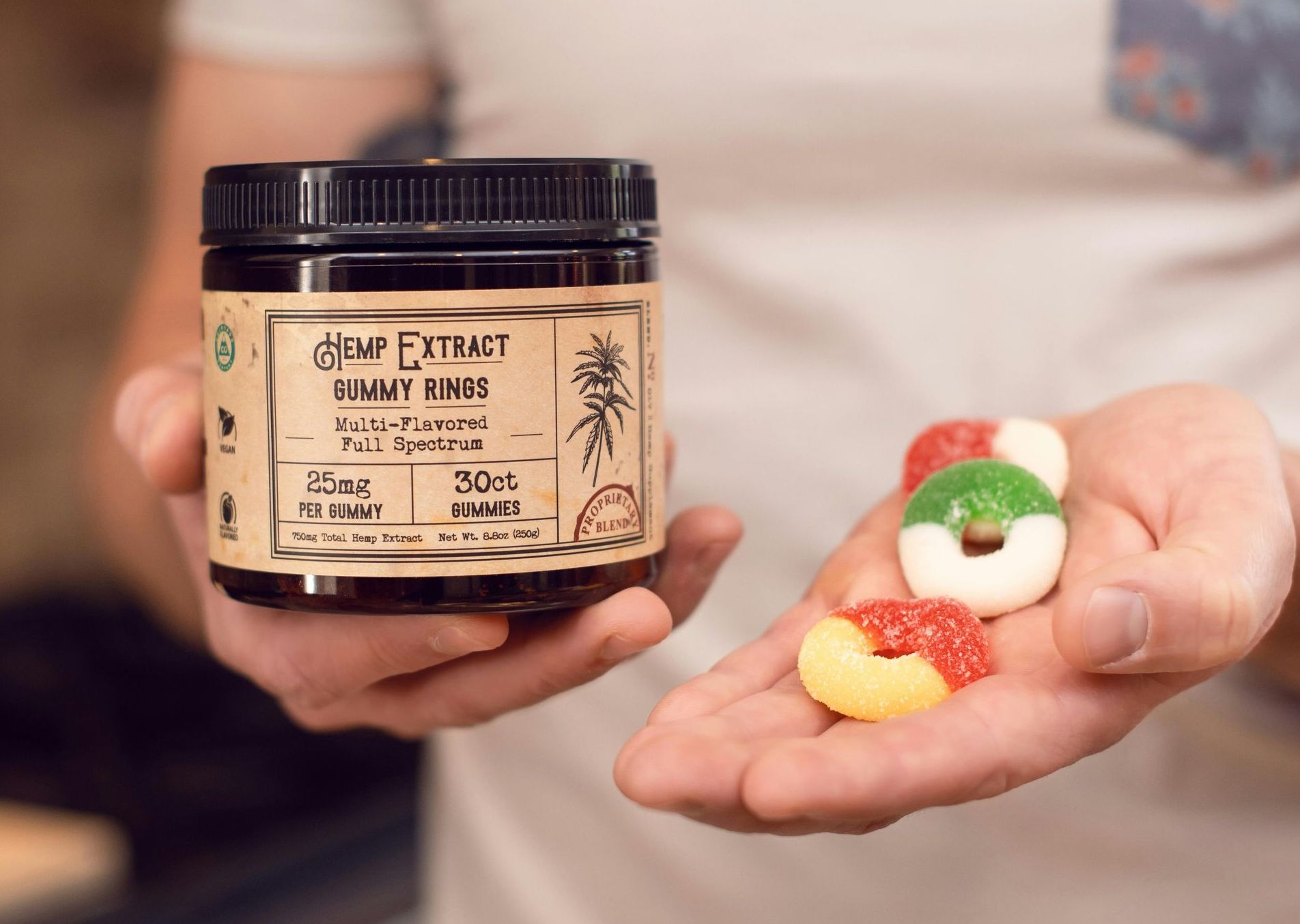 A person is holding a jar of gummy bears in their hand.