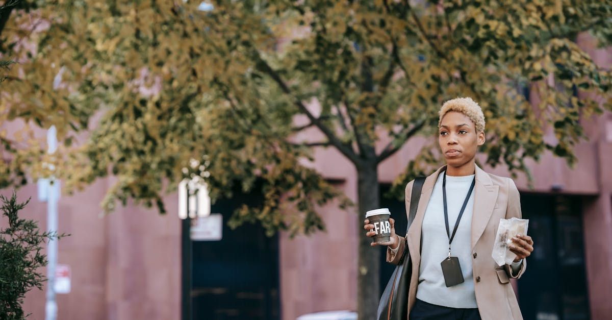 A woman is walking down the street holding a cup of coffee.