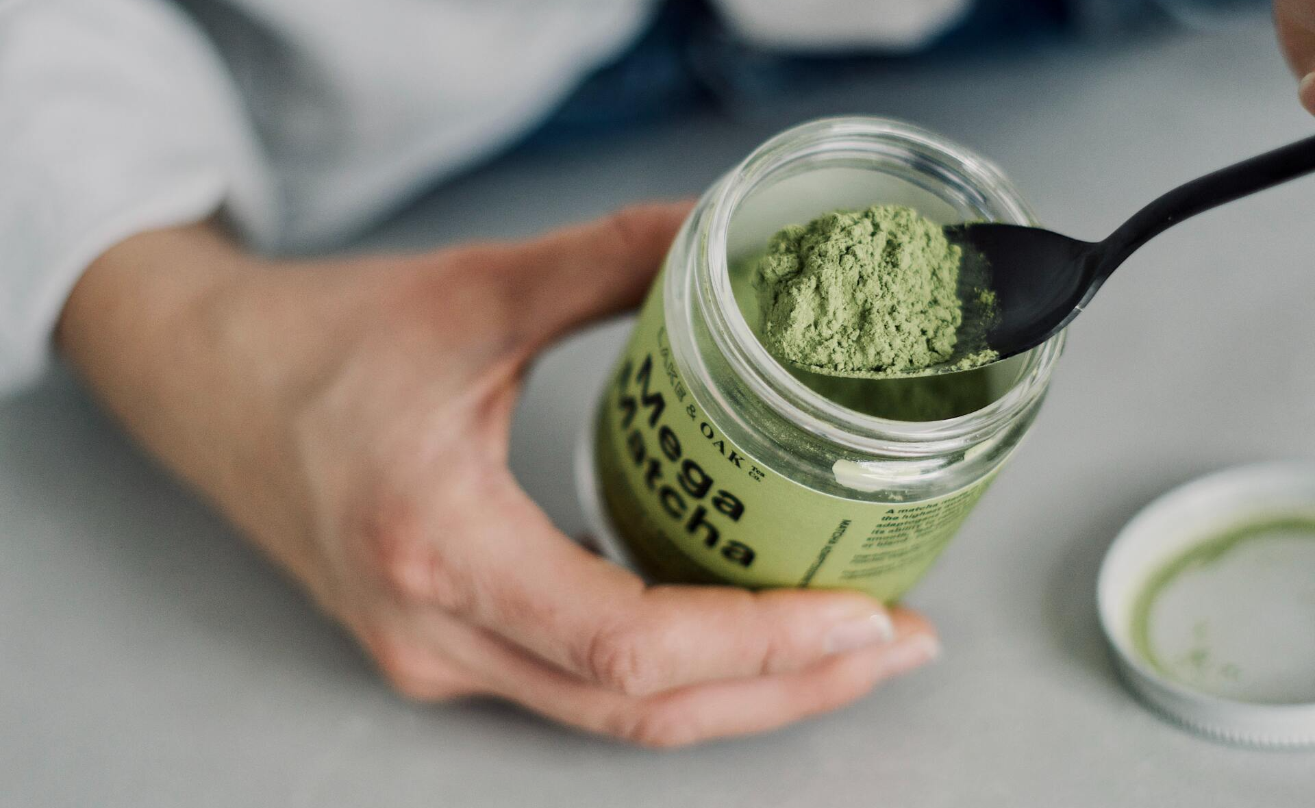 Spoon of mega matcha powder from a jar.