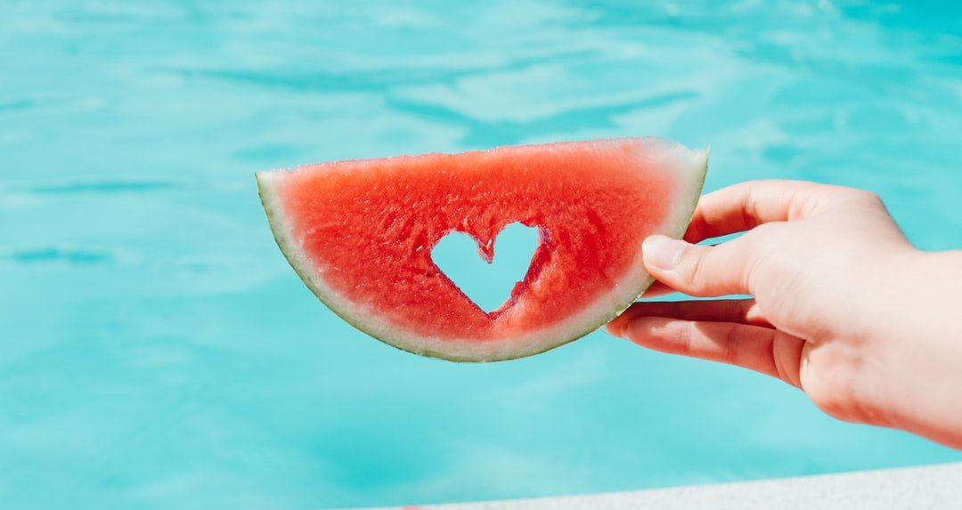 Slice of watermelon with heart shape cut out of it.