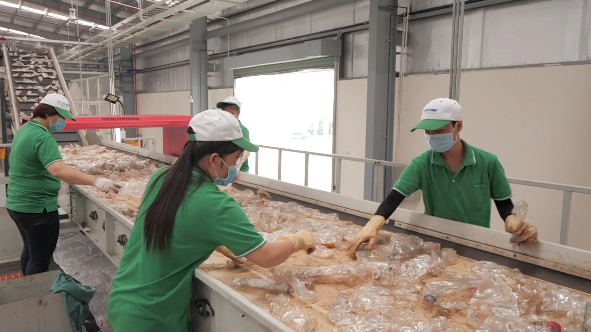 Duytan professionals manually sorting plastic waste on a conveyor belt.