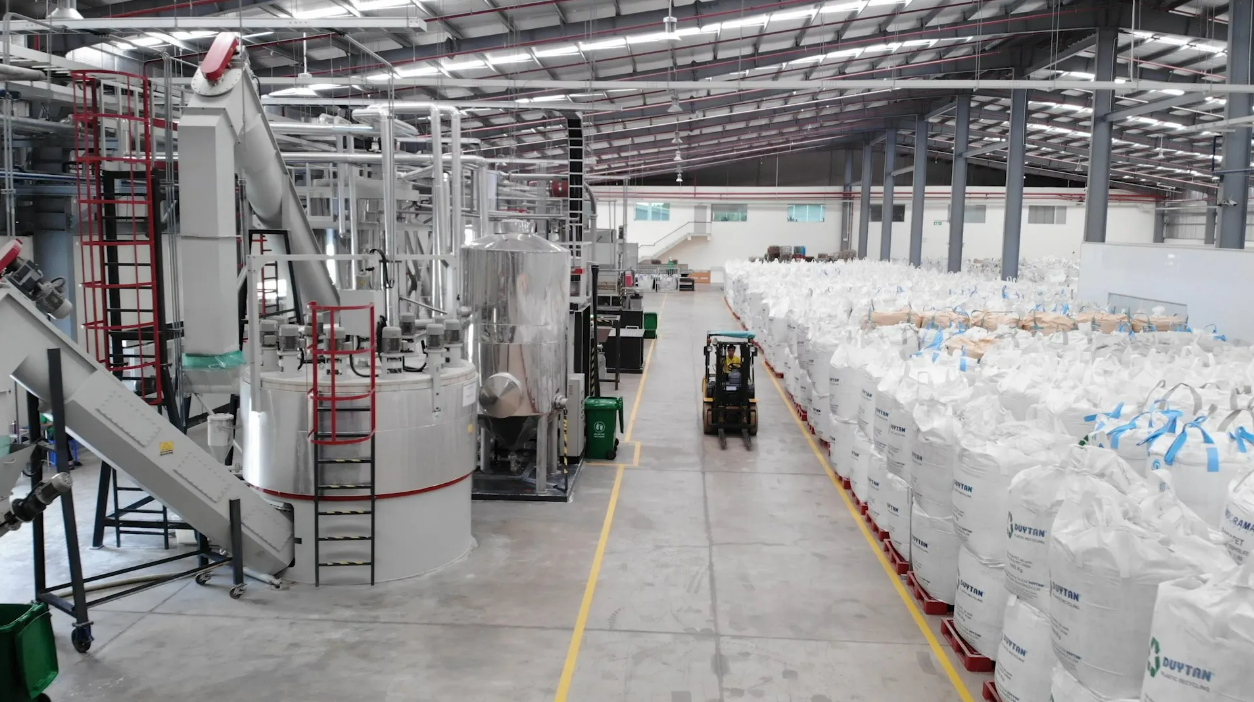 Duytan/Plascene recycling facility with forklift driving between recycling equipment and stacks of recycled rPET resin.