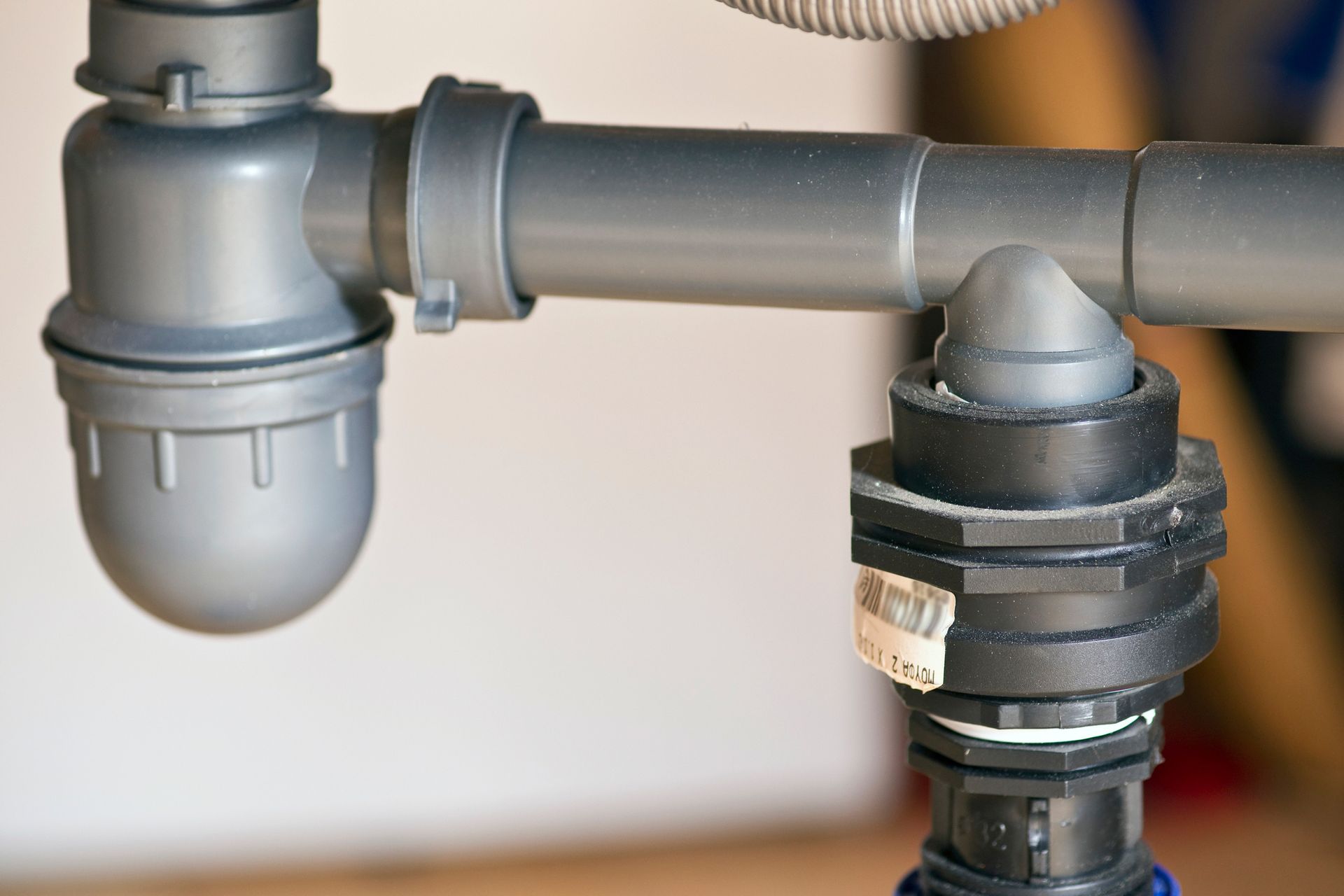 Close-up of gray and black plumbing pipes and fittings under a sink.