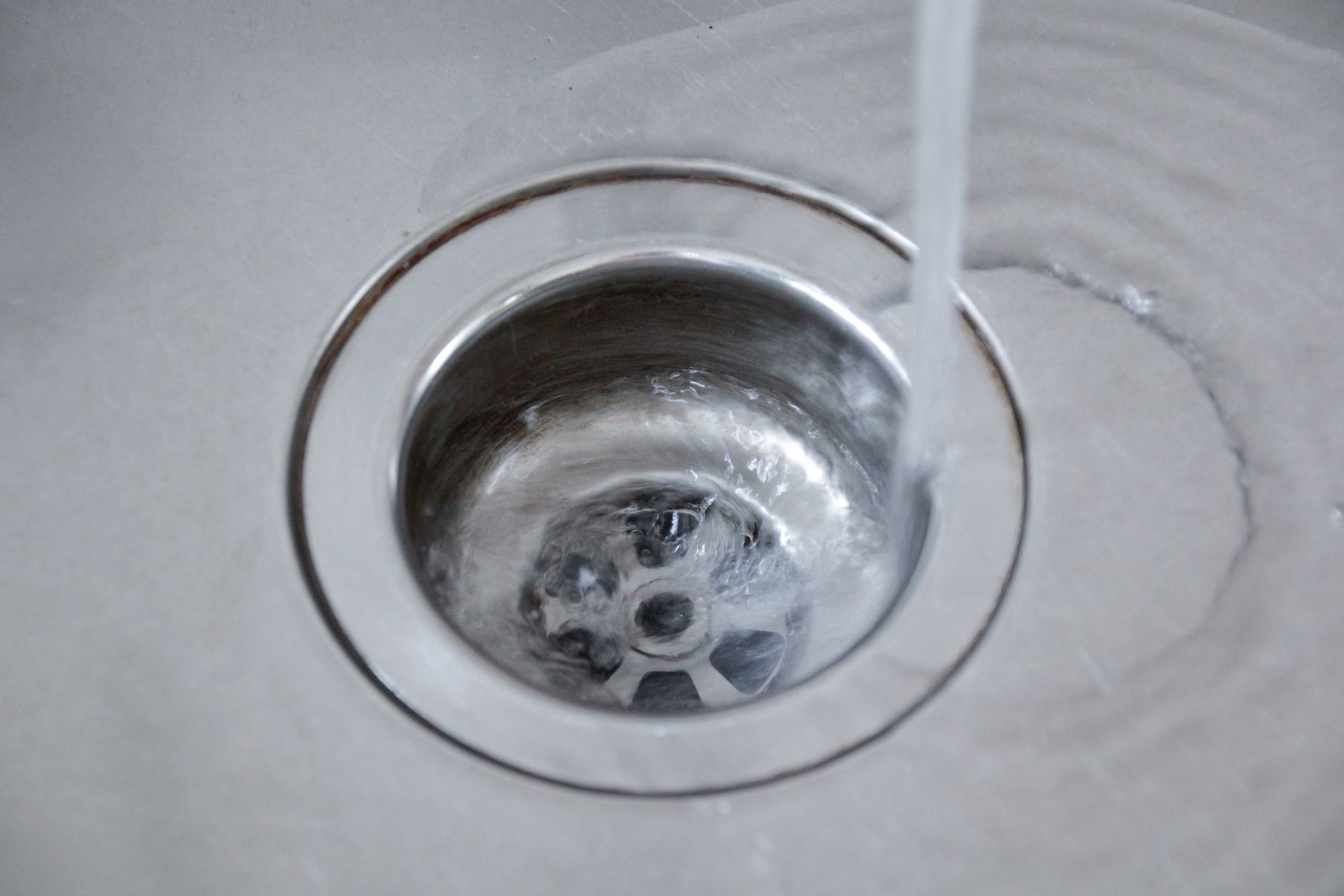 Water flowing down a silver sink drain.