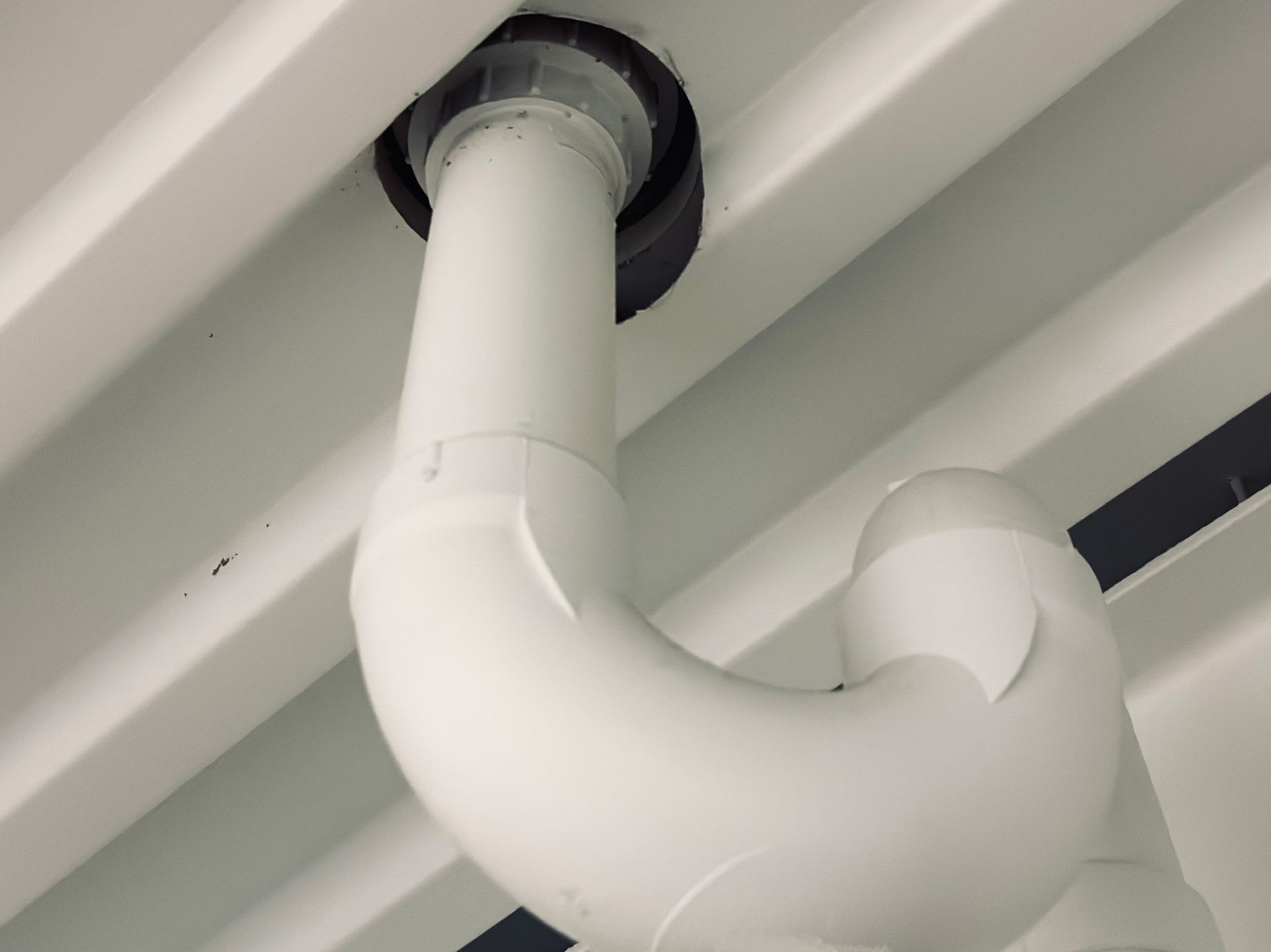 White PVC pipe forming a U-shape, protruding from a ceiling.