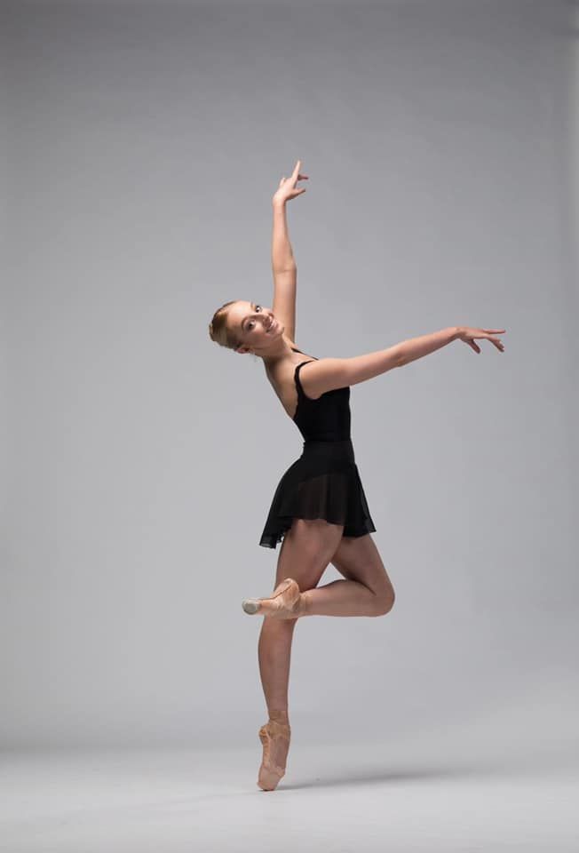 Ballet Dancer in Black Leotard, en Pointe, Arm Raised, Smiling — Kay Flynn Dancing Academy Southport in Southport, QLD