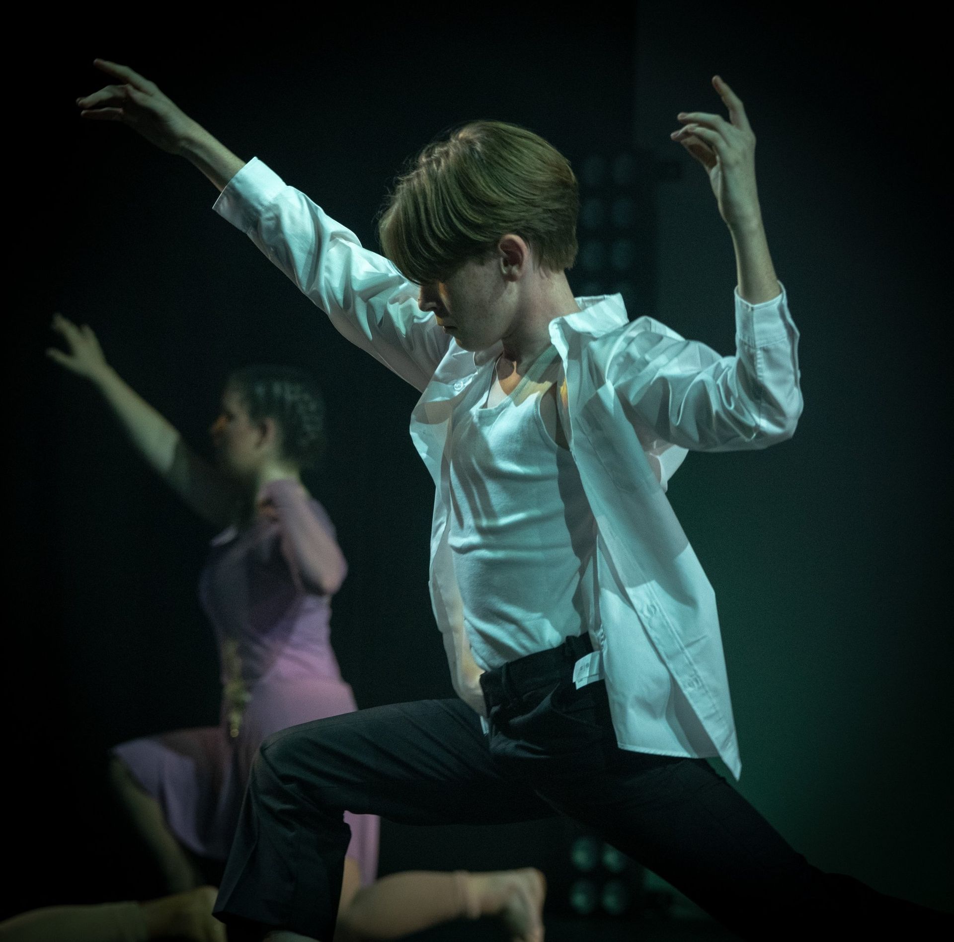 Dancer in White Shirt and Black Pants Kneels, Arm Raised — Kay Flynn Dancing Academy Southport in Southport, QLD